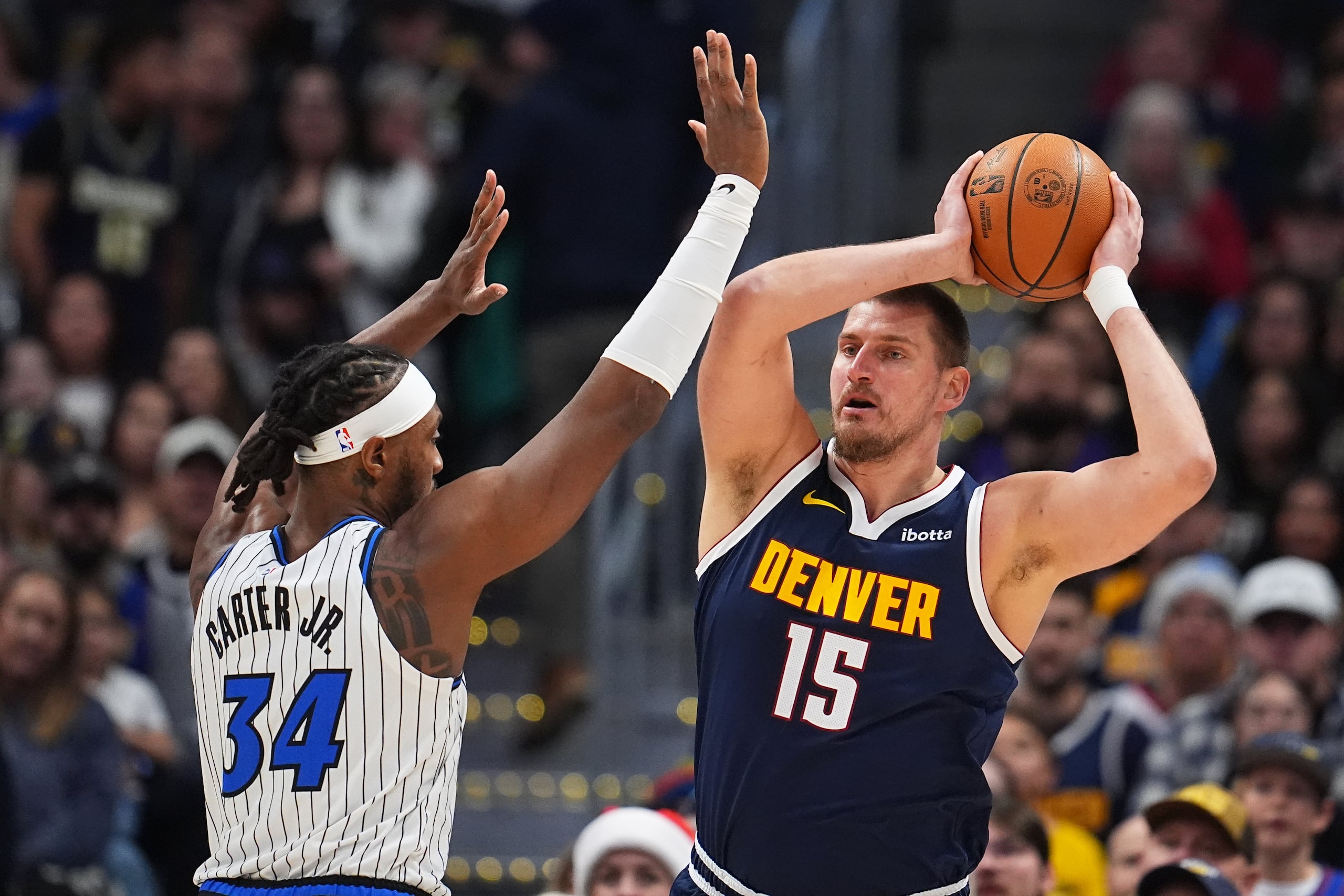 El serbio Nikola Jokic, de los Nuggets de Denver, busca enviar un pase frente a Wendell Carter Jr., del Magic de Orlando.