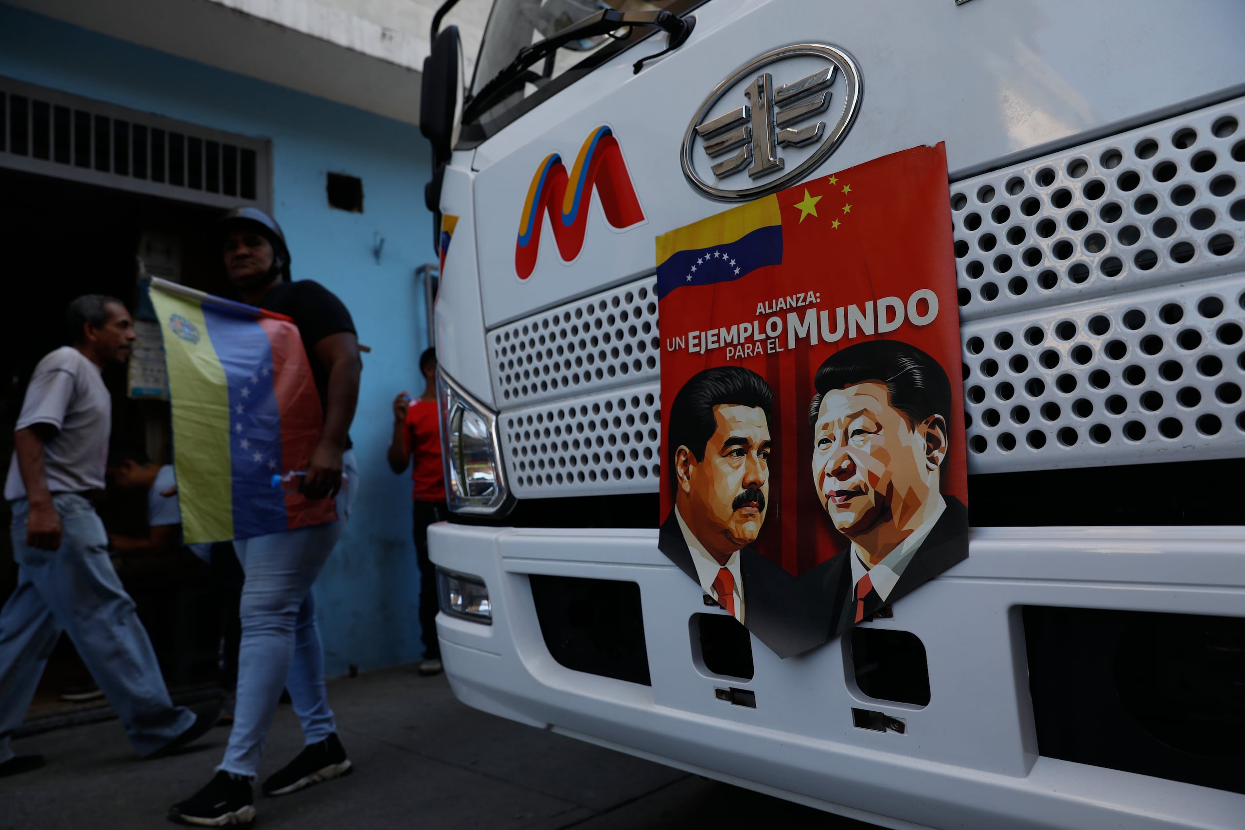 Una pancarta en la parte delantera de un autobús muestra imágenes del presidente venezolano, Nicolás Maduro, y del mandatario chino, Xi Jinping, con el mensaje: "Un ejemplo para el mundo", durante una manifestación organizada por el gobierno en contra de la intervención estadounidense, el sábado 13 de diciembre de 2025, en Caracas, Venezuela. (AP Foto/Cristian Hernández)