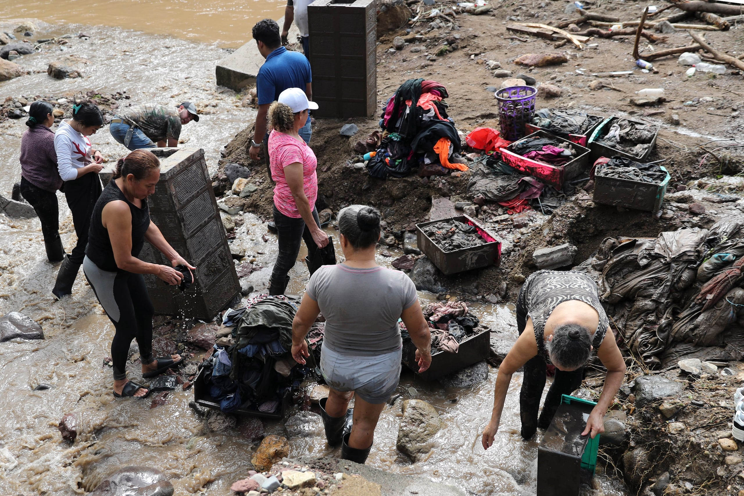Personas limpian objetos rescatados de las casas afectadas por inundaciones en la aldea Rio Abajo este viernes, en Tegucigalpa (Honduras). EFE/ Gustavo Amador