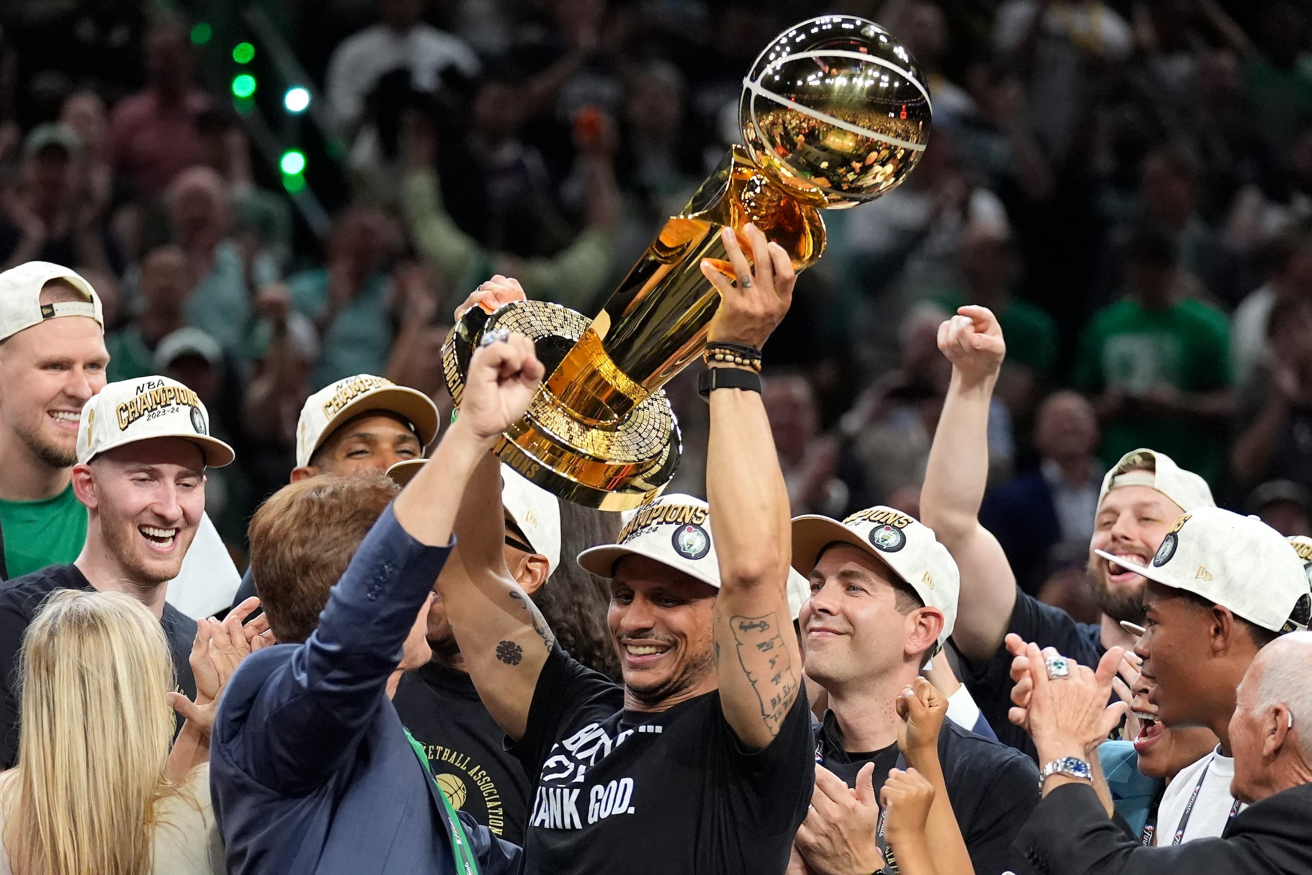 El dirigente de los Celtics de Boston Joe Mazzulla, levanta el trofeo Larry O'Brien en medio de la celebración de los Celtics de Boston.