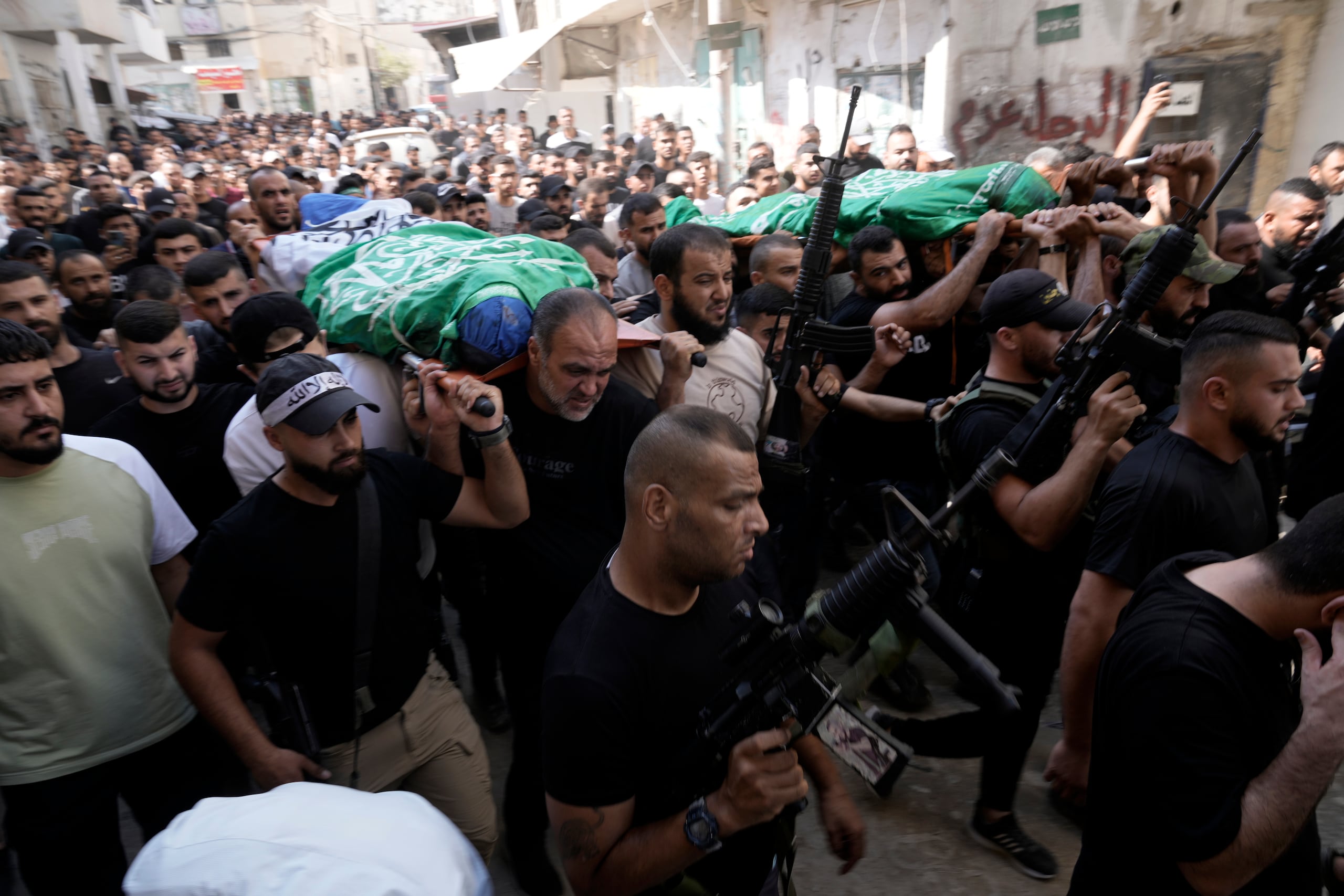 Dolientes marchan durante un funeral con los cadáveres de los palestinos Ahmed Abu Arra, izquierda, del poblado de Aqaba, y Raafat Dawasa, oriundo de Silat Al-Harithiya, ambos envueltos en la bandera de Hamás y asesinados en un ataque israelí en el campamento de refugiados de Jenin, Cisjordania, el domingo 18 de agosto de 2024. (AP Foto/Majdi Mohammed)