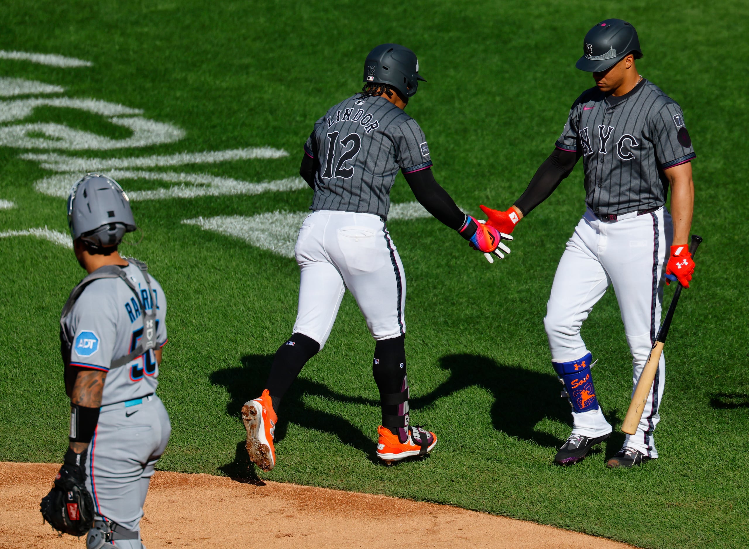 Francisco Lindor (12) choca manos con Juan Soto después de pegar un jonrón solitario en la primera entrada.