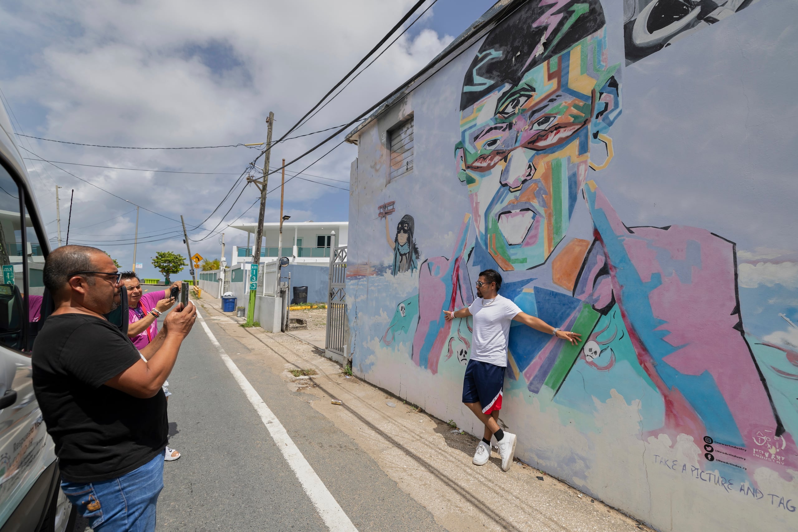 Una persona que participa en una visita guiada posa para una foto delante de un mural de Bad Bunny en Playa Puerto Nuevo, en Vega Baja, Puerto Rico, el 12 de agosto de 2025. (AP Foto/Alejandro Granadillo)