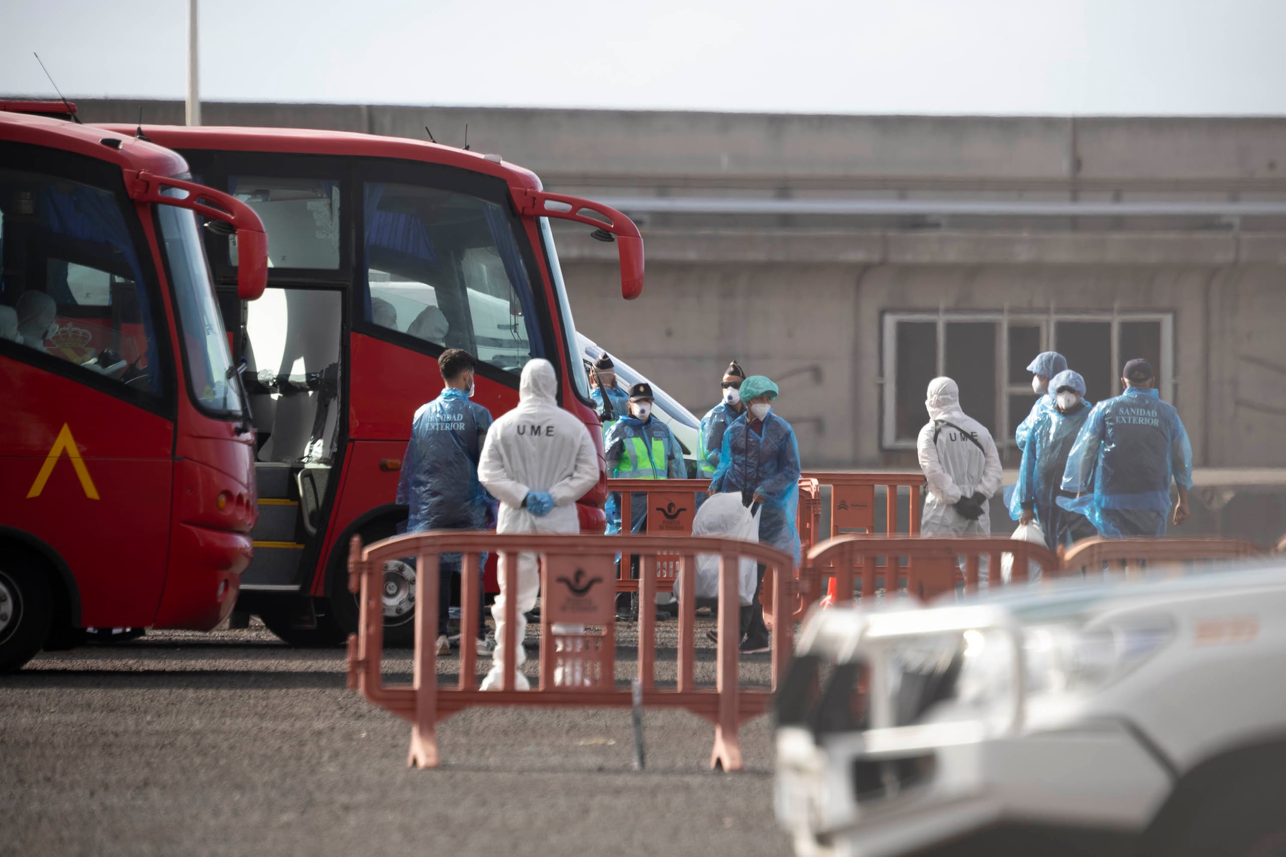 Dos de los pasajeros desembarcados que iban a bordo del crucero neerlandés MV Hondius han desembarcado ya en el puerto de Granadilla de Abona y reciben instrucciones de personal de la Unidad Militar de Emergencias y del Servicio de Sanidad Exterior. EFE/Miguel Barreto