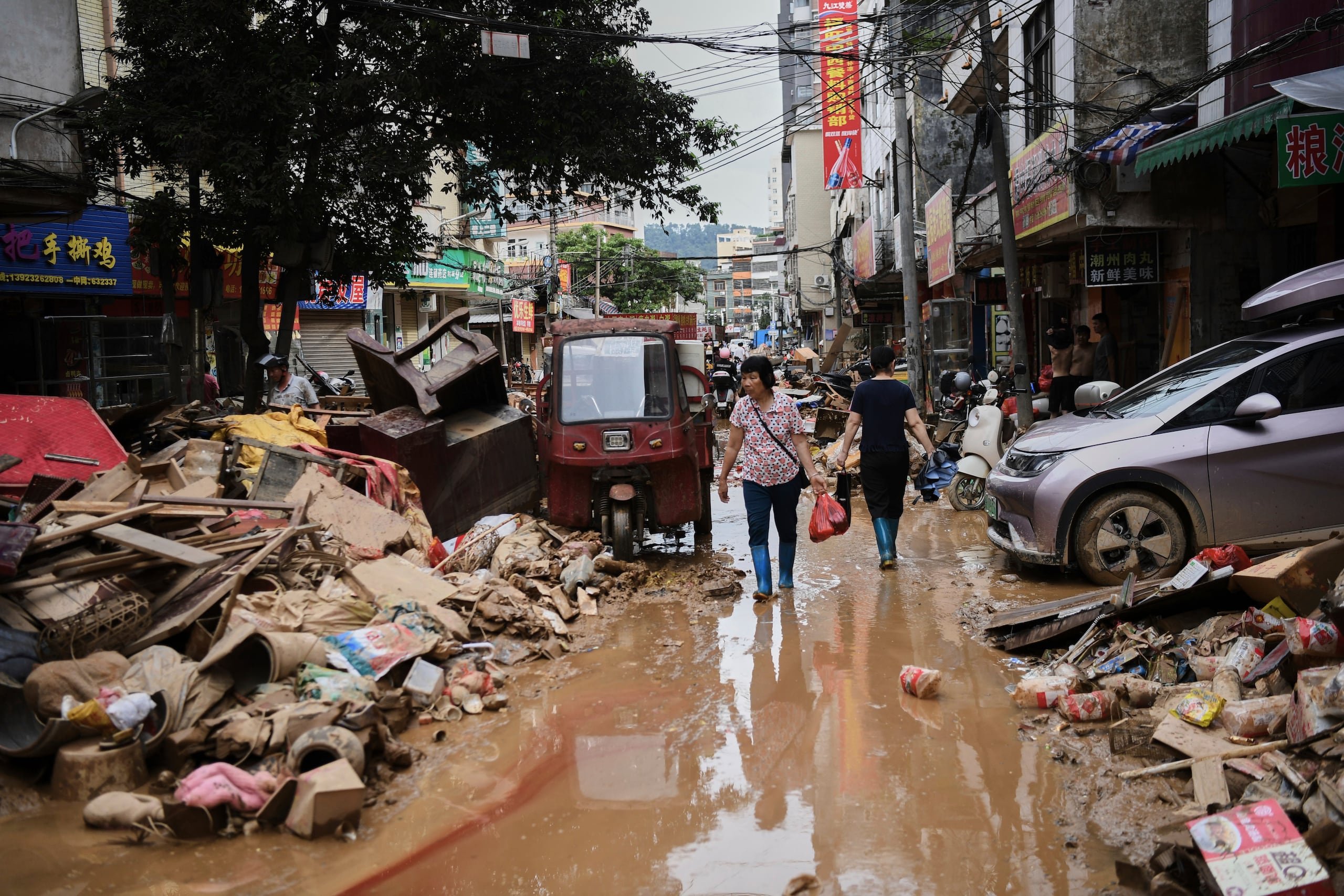 ARCHIVO - En esta imagen, distribuida por la agencia noticiosa estatal Xinhua, residentes cruzan una calle anegada llena de escombros tras el desbordamiento de un río después de días de intensas precipitaciones, en el condado de Huaiji, en la provincia de Guangdong, en el sur de China, el 19 de junio de 2025. (Deng Hua/Xinhua vía AP, archivo)