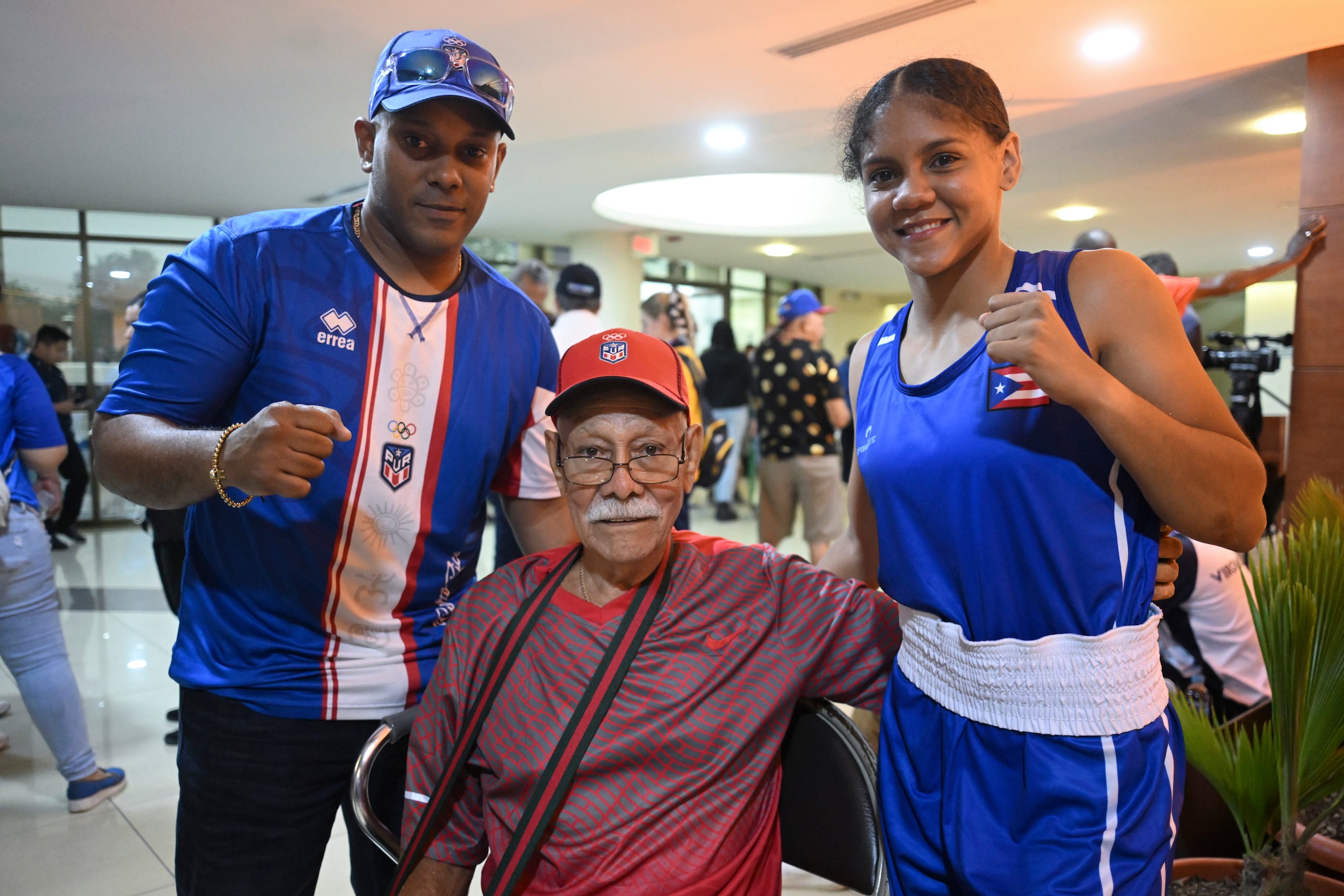 Krystal Rosado, compartiendo con su entrenador Gerardo Sánchez Orta (izquierda) y Gerardo Sánchez Robles, fundador del gimnasio Villa Fontana de Carolina, se puede ver aquí en unos de los salones que servía de entrada al área de competencia.