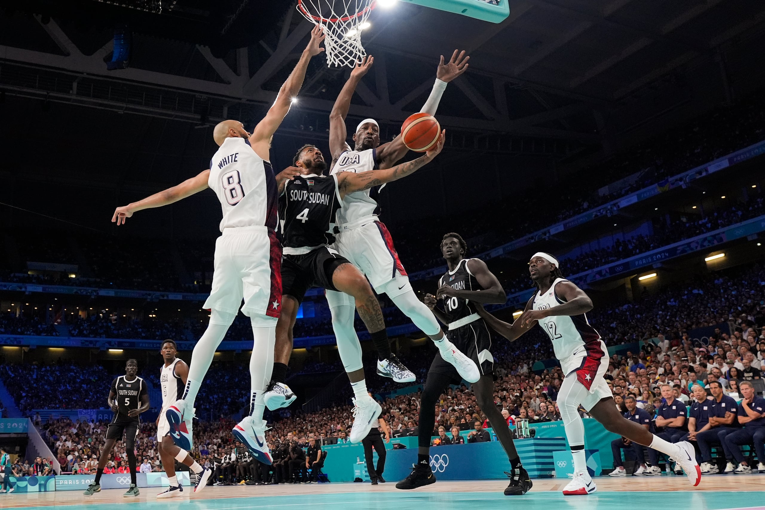 Carlik Jones, de Sudán del Sur, recibe un tapón de parte de Derrick White y Bam Adebayo.