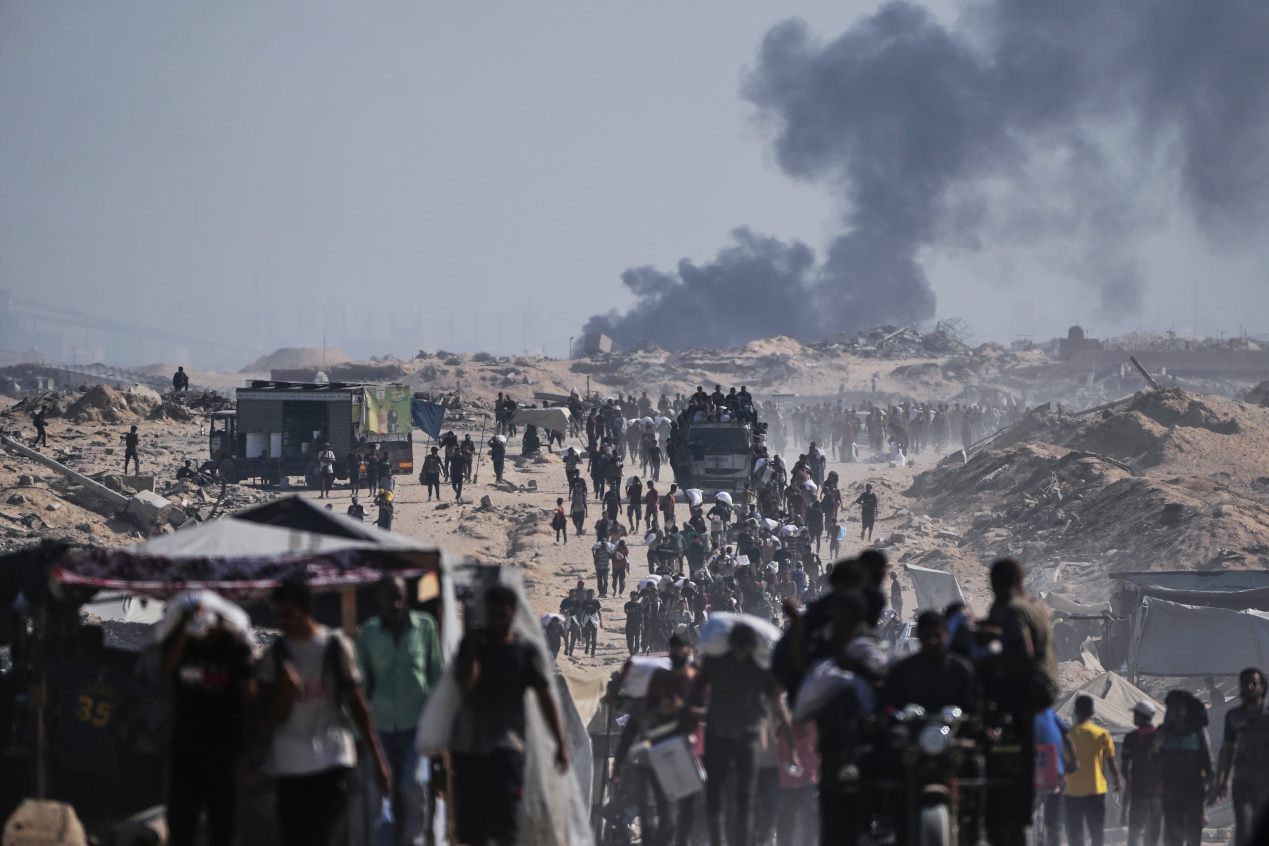 Varios Palestinos cargan sacos de harina descargados de un convoy de ayuda humanitaria en las afueras de Beit Lahiya, en el norte de la Franja de Gaza, el sábado 23 de agosto de 2025. (AP Foto/Abdel Kareem Hana)