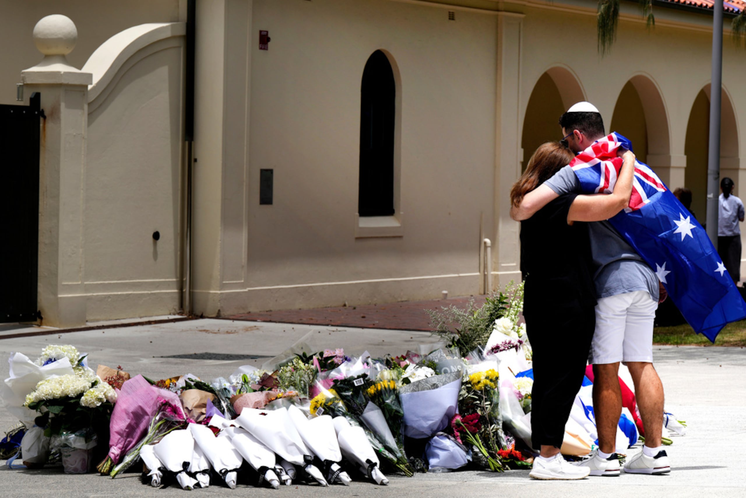 Una pareja coloca flores como homenaje a las víctima de un tiroteo ante el Bondi Pavilion en el distrito de Bondi Beach, Sydney, el lunes 15 de diciembre de 2025, al día siguiente de la balacera.
