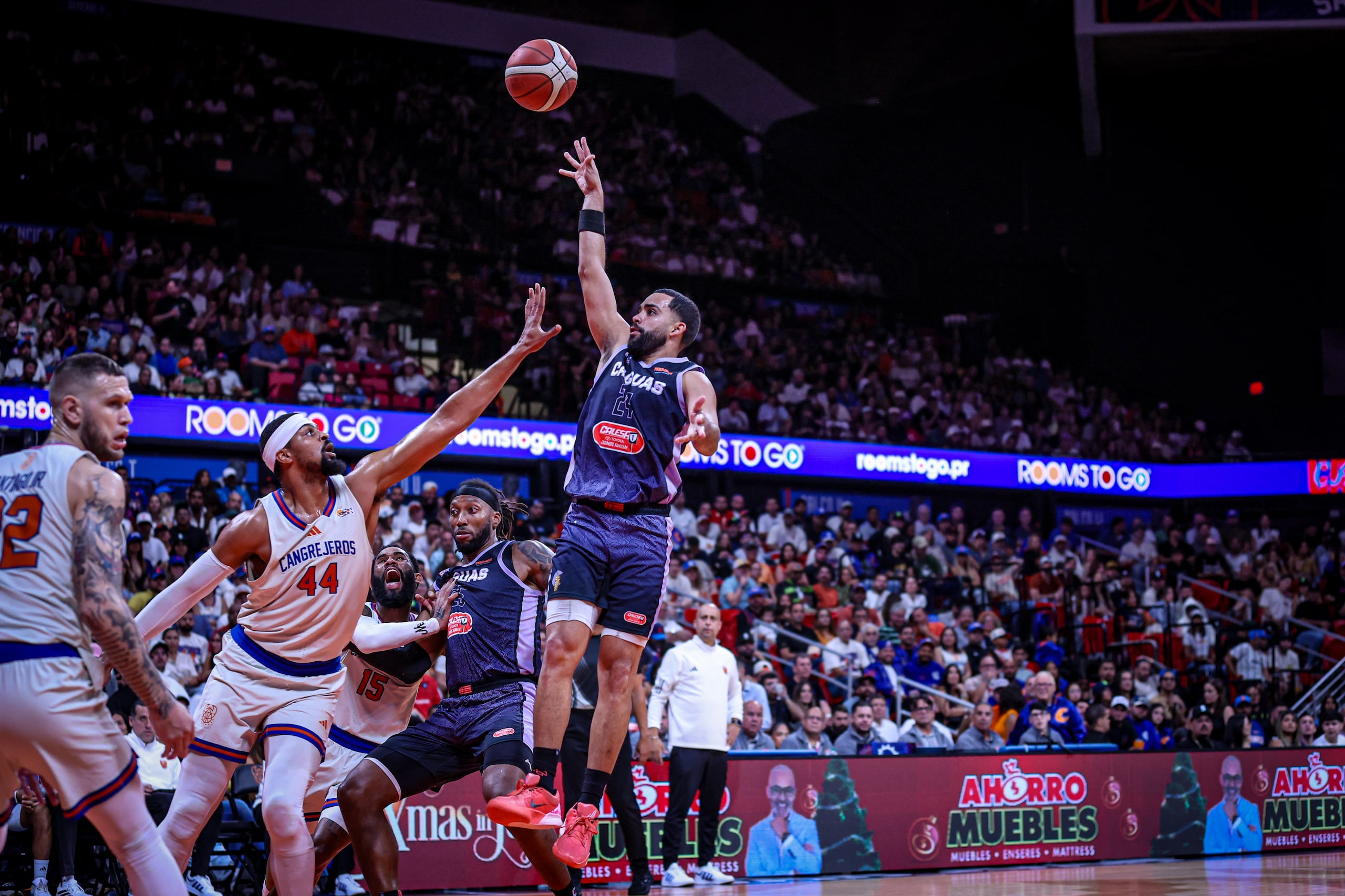 Christian "Cuco" López tira al canasto contra Devon Collier, excompañero de equipo ahora con los Cangrejeros de Santurce.