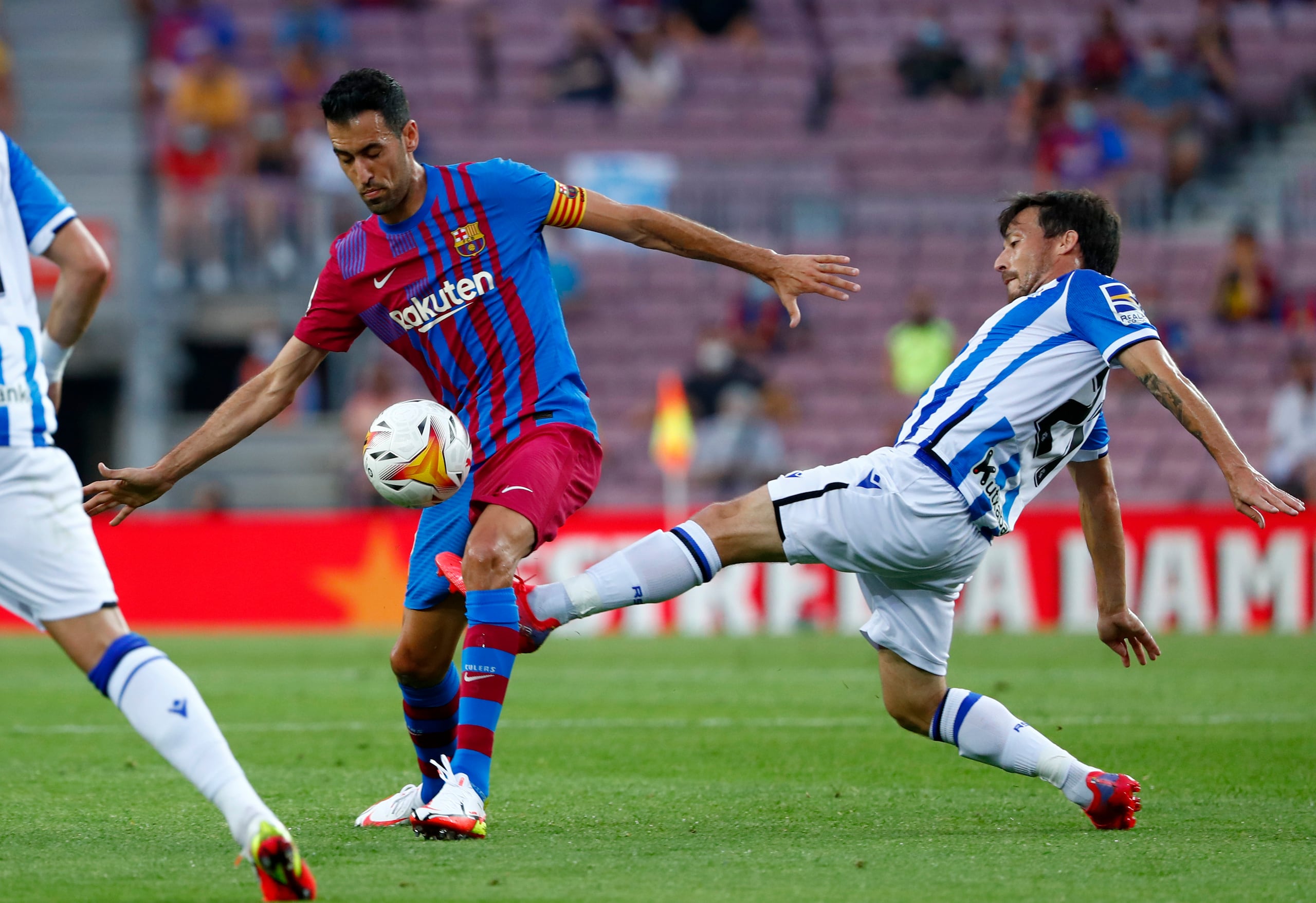 David Silva (derecha) de la Real Sociedad pugna por el balón con Sergio Busquets del Barcelona en un partido de la Liga de España, el domingo 15 de agosto de 2021.