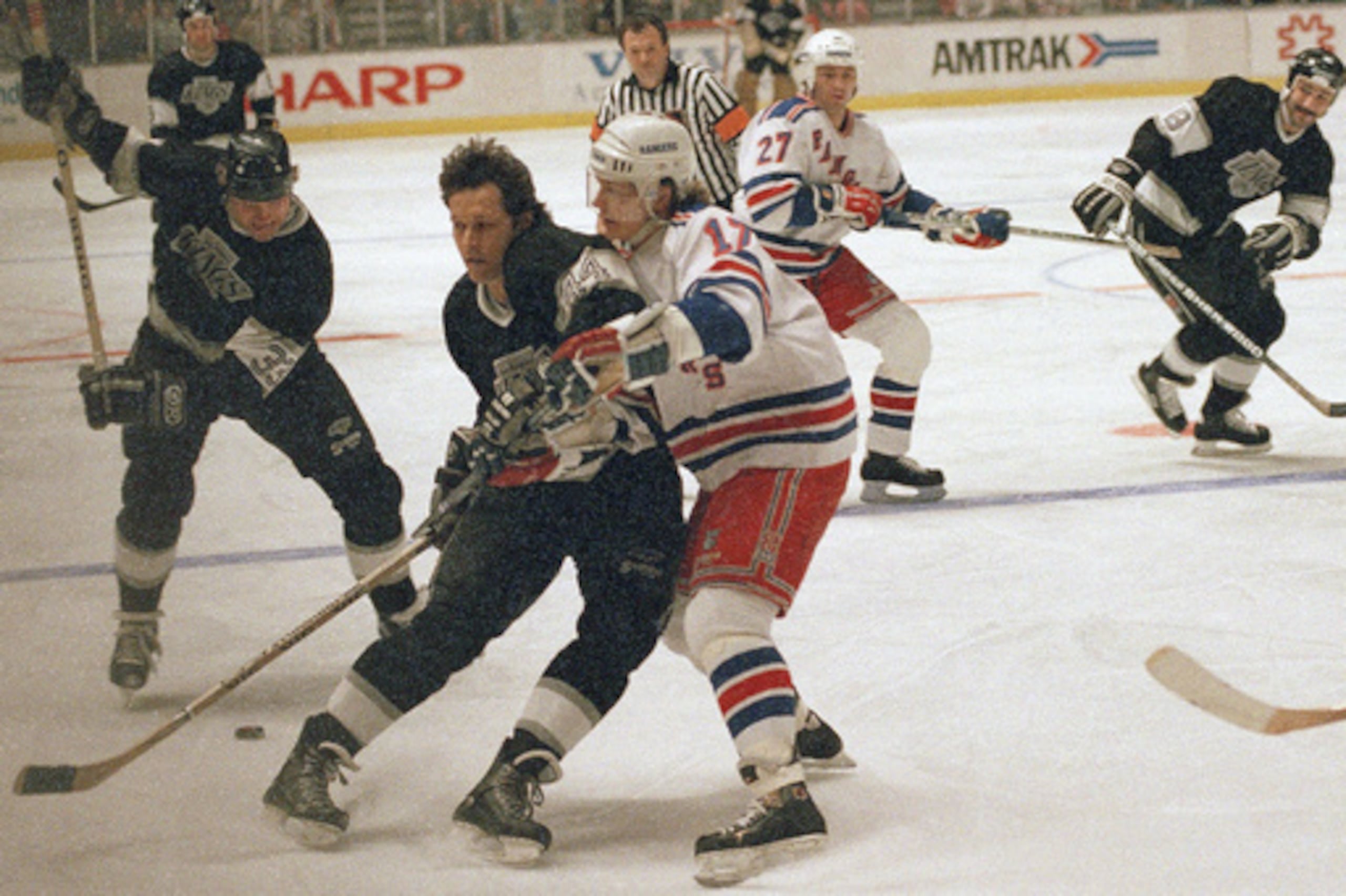 ARCHIVO - Marty McSorley, a la izquierda, de los Los Angeles Kings, toma impulso antes de lanzar el disco, mientras su compañero Ron Duguay, en el centro, bloquea a Carey Wilson, de los New York Rangers, durante el primer periodo del partido de la Liga Nacional de Hockey celebrado el lunes 27 de febrero de 1989 en Nueva York. (Foto AP/Ron Frehm, archivo)