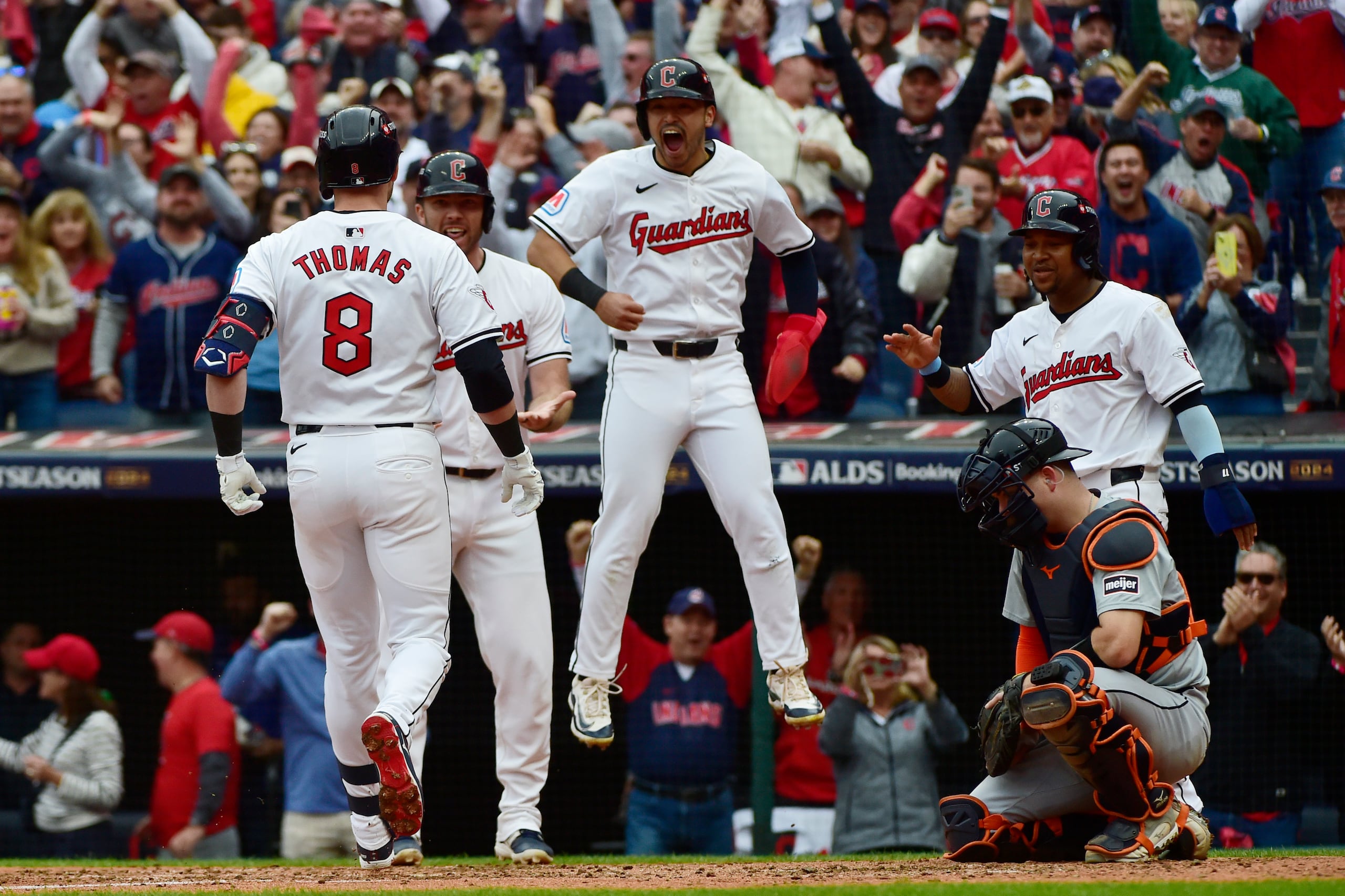 David Fry, Steven Kwan y José Ramírez felicitan a Lane Thomas después de conectar un grand slam en el quinto juego de la Serie Divisional contra los Tigers.