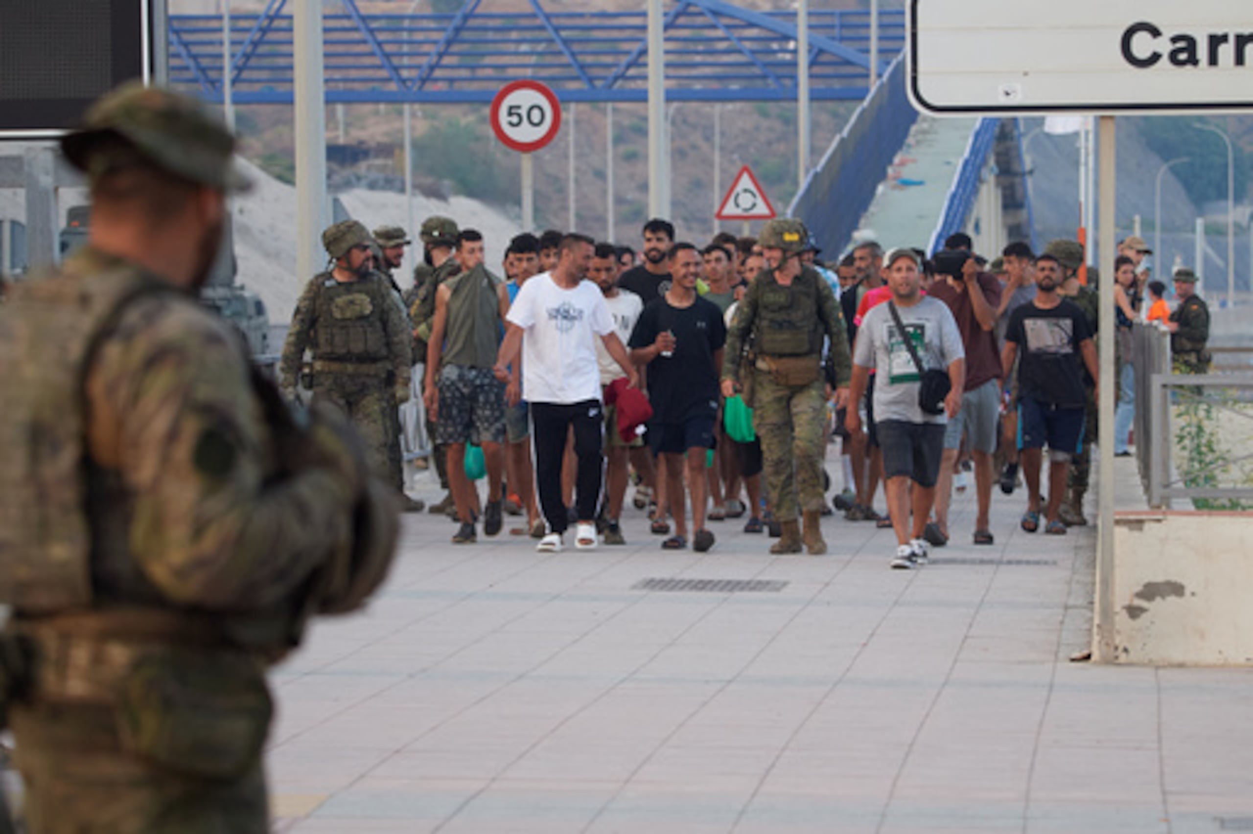 Militares españoles escoltan a los migrantes que cruzaron a España de vuelta a Marruecos desde el enclave español de Ceuta, el sábado 1 de agosto de 2026. (Foto AP/Antonio Sempere)