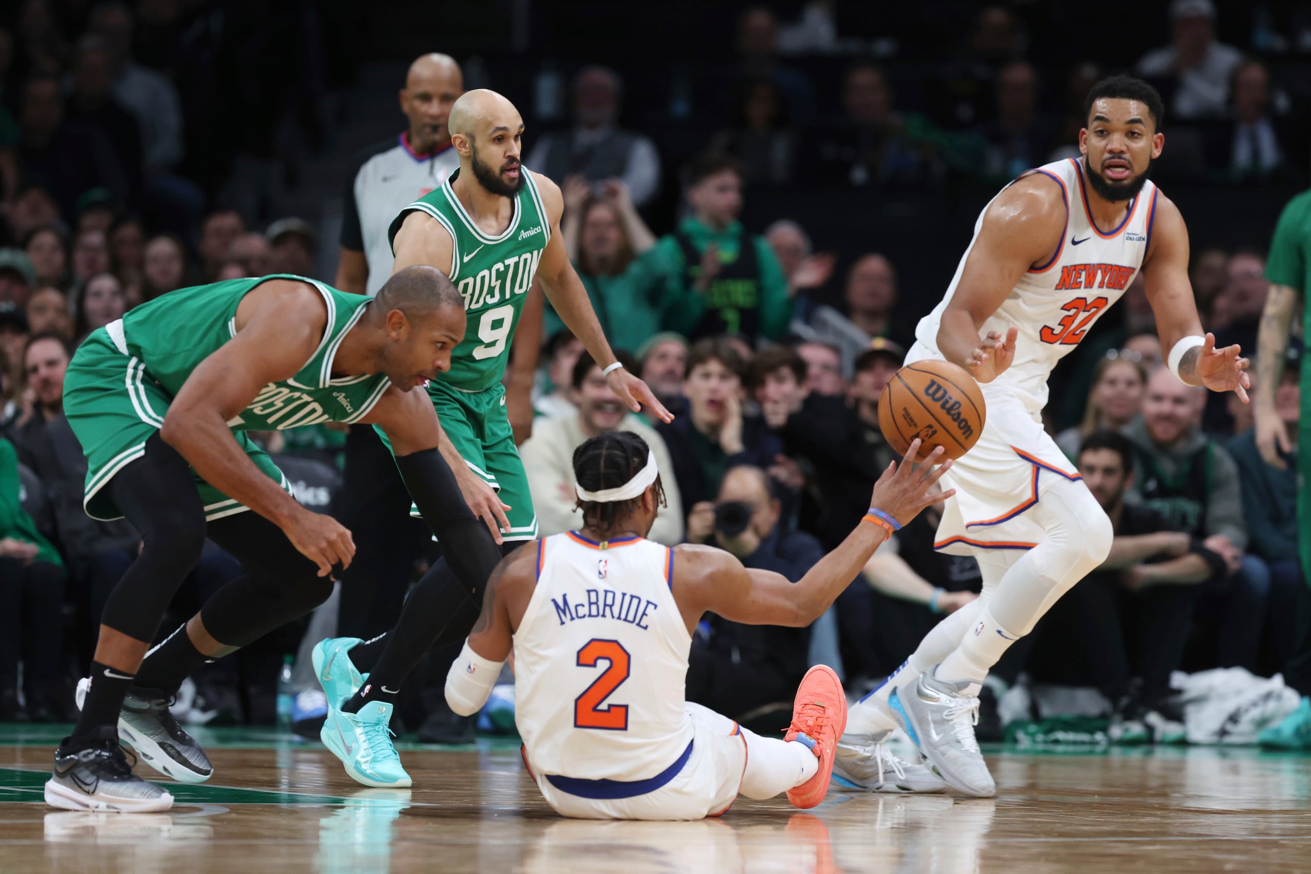 Miles McBride (2), de los Knicks de Nueva York, pasa el balón a Karl-Anthony Towns (32) ante la presión defensiva de Al Horford, izquiera, y Derrick White (9), de los Celtics de Boston, durante la segunda mitad del partido de baloncesto de la NBA, el domingo 23 de febrero de 2025, en Boston. (AP Foto/Michael Dwyer)