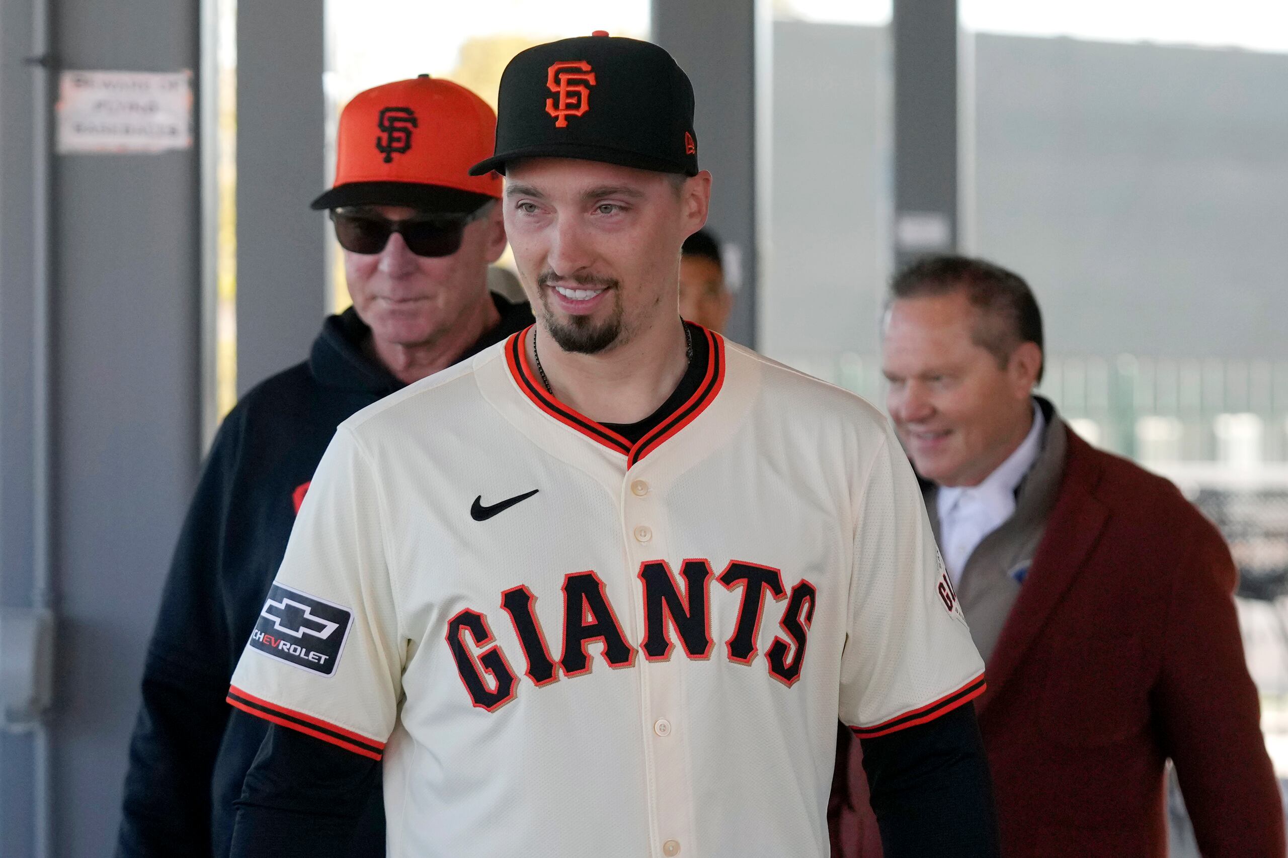 El nuevo lanzador de los Gigantes de San Francisco Blake Snell (centro) camina junto al mánager de los Gigantes Bob Melvin (izquierda), y el agente de Snell Scott Boras (derecha), previo a ser presentado en la conferencia de prensa.