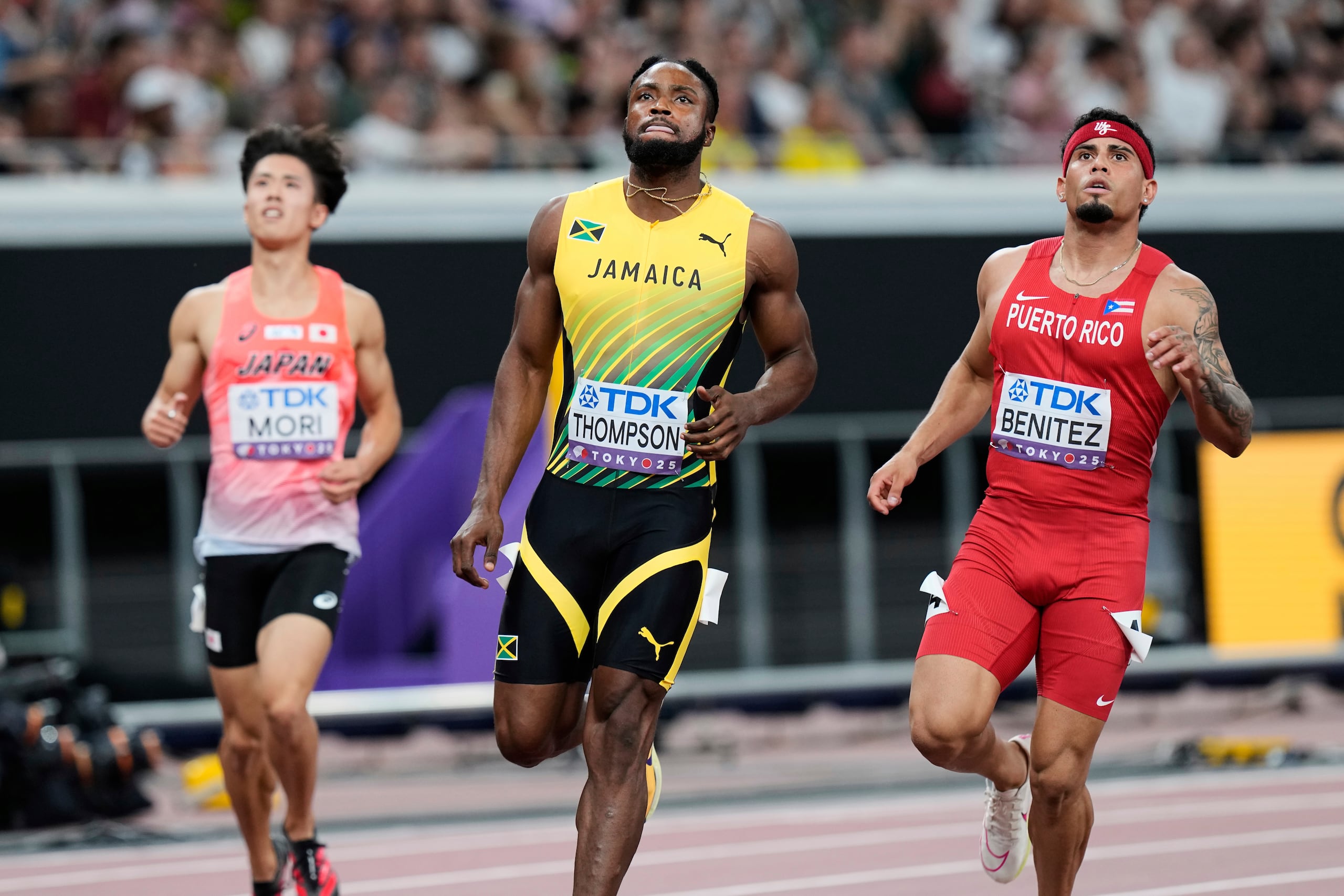 El boricua Eloy Benítez, a la derecha, junto al jamaiquino Kishane Thompson y el japonés Yuhi Mori, llegando a la meta en una de las preliminares de 100 metros en el Mundial de Tokio.
