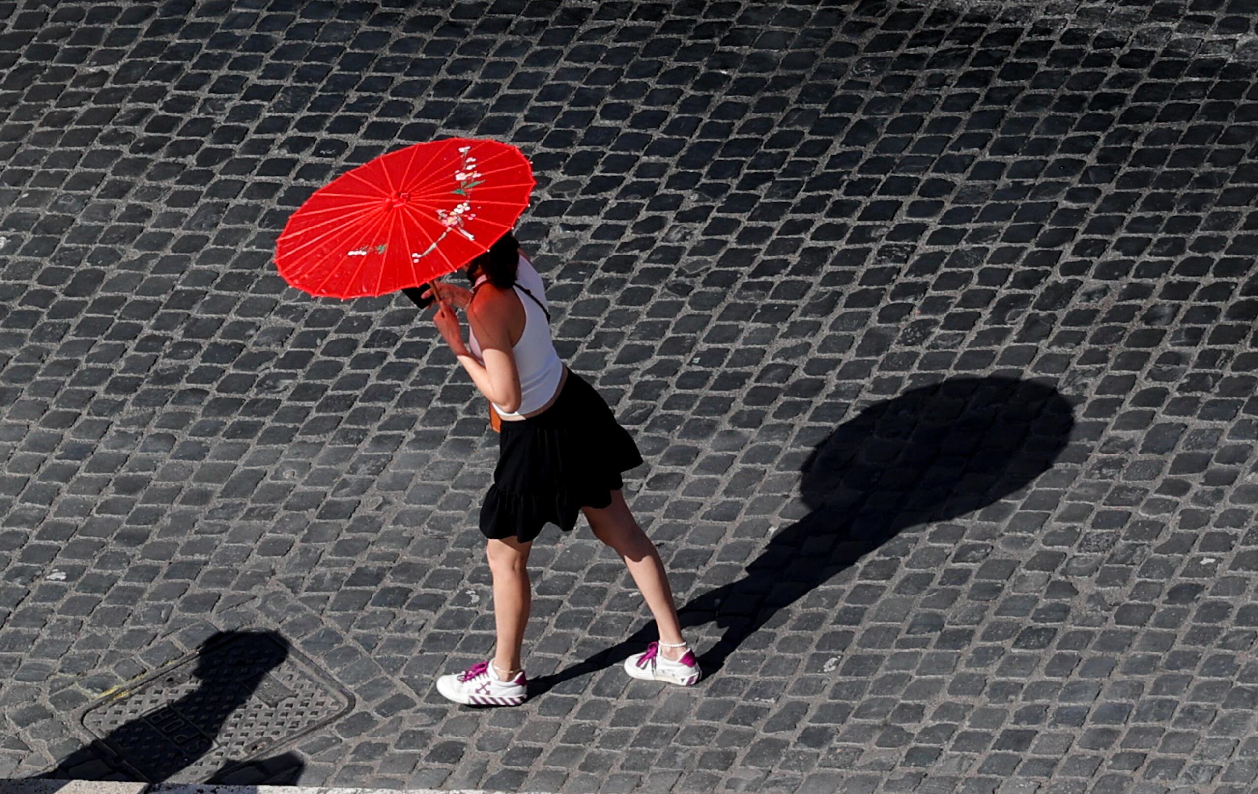 En la imagen del pasado domingo, una mujer porta una sombrilla para protegerse del sol en un caluroso día en Roma. (EFE/GIUSEPPE LAMI)