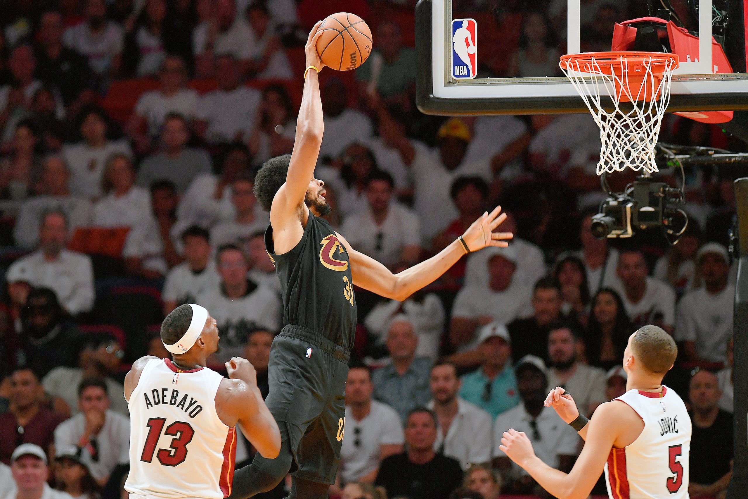 Jarrett Allen, de los Cavaliers de Cleveland, donquea frente a Bam Adebayo y Nikola Jovic, del Heat de Miami.