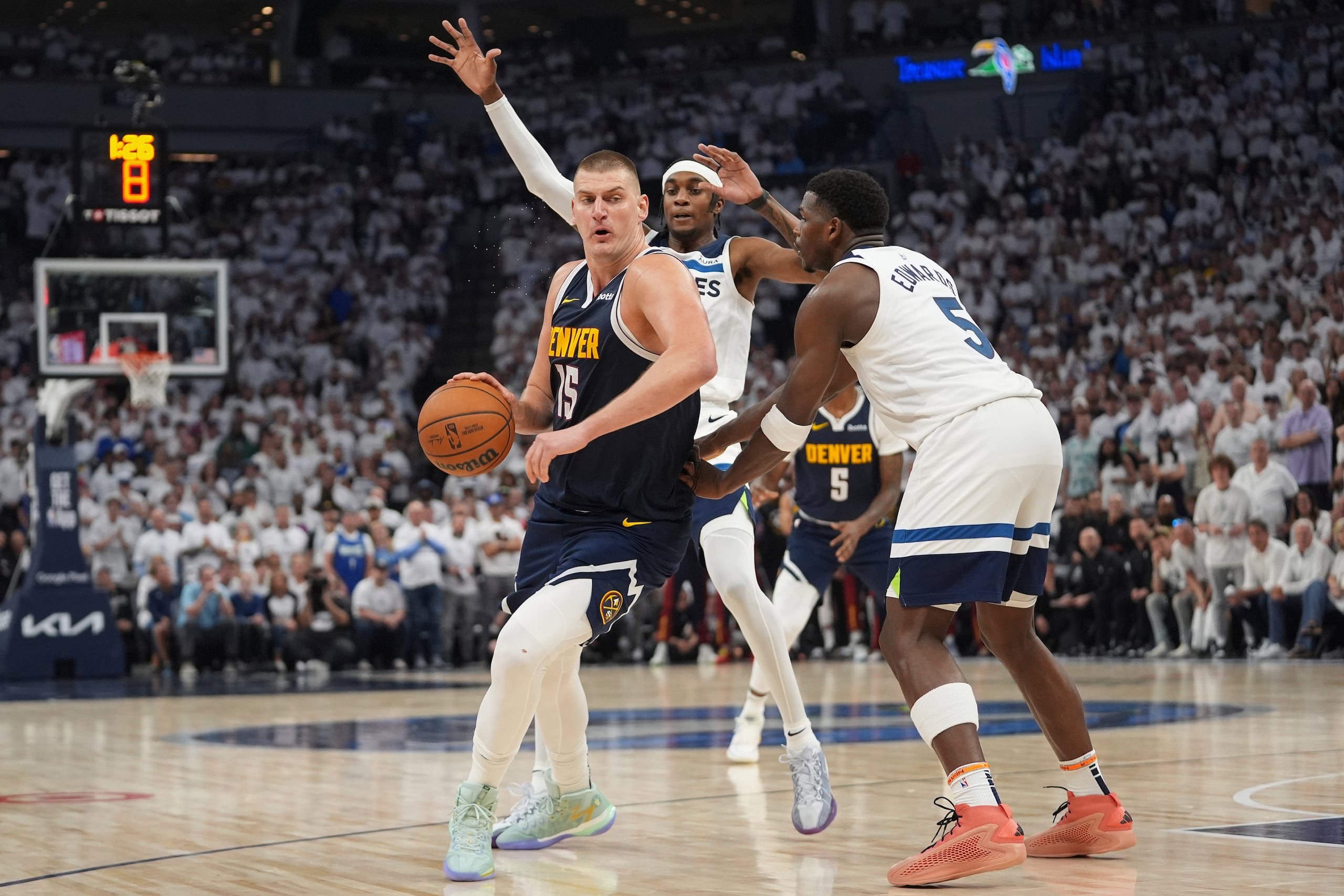 Nikola Jokic, izquierda, de los Nuggets de Denver, trabaja hacia la canasta con la presión de Jaden McDaniel y Anthony Edwards, de los Timberwolves de Minnesota, durante la segunda mitad de la serie de semifinales de la Conferencia Oeste, el domingo 12 de mayo de 2024, en Minneapolis. (AP Foto/Abbie Parr)