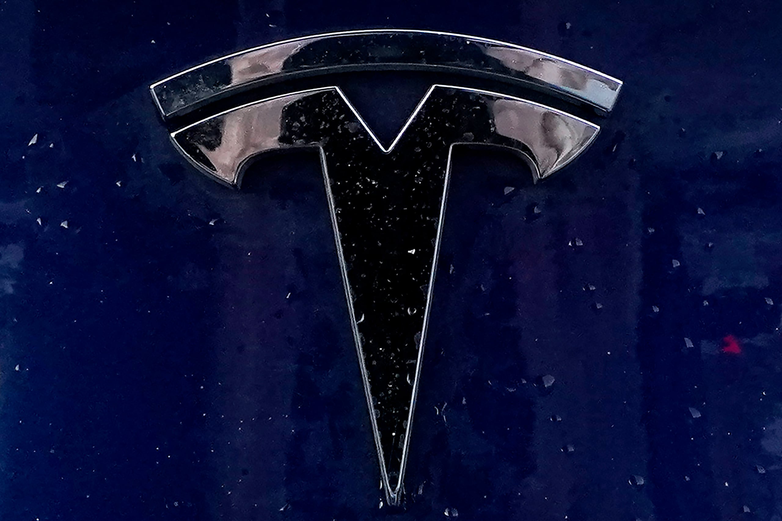 ARCHIVO - El emblema de un vehículo eléctrico Tesla yace sobre uno de ellos el domingo 21 de febrero de 2021, en Boston. (Foto AP/Steven Senne)