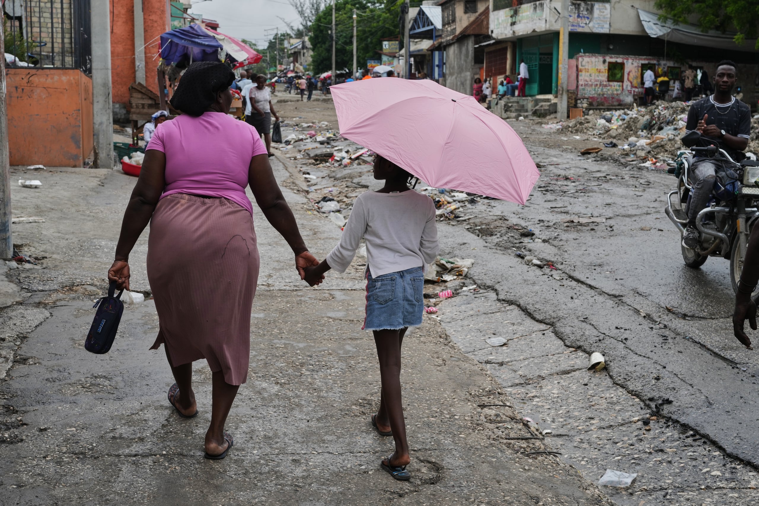 Una mujer sostiene a una niña con un paraguas en la mano durante una lluvia ligera en Puerto Príncipe, Haití, el jueves 23 de octubre de 2025. (Foto AP/Odelyn Joseph)