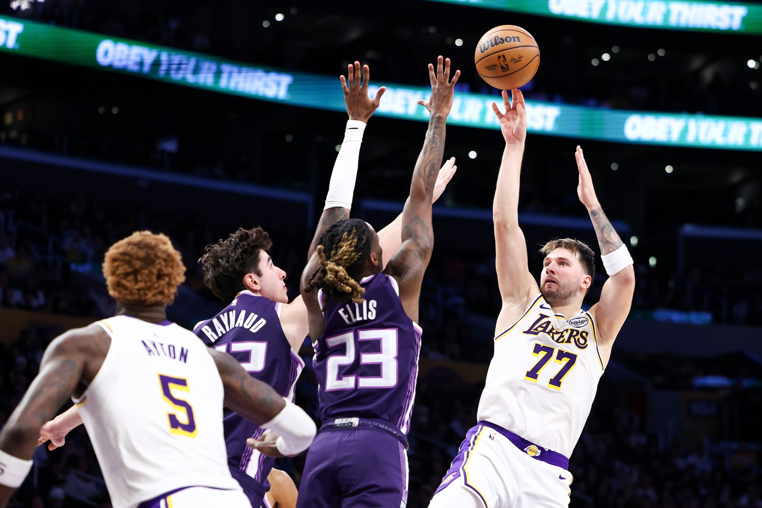 Luka Doncic (77), de los Lakers de Los Ángeles, dispara sobre Maxime Raynaud, izquierda, y Keon Ellis (23), de los Kings de Sacramento, mientras Deandre Ayton (5), de los Lakers, observa durante la primera mitad del juego de baloncesto de la NBA, el domingo 1 de marzo de 2026, en Los Ángeles. (AP Foto/Jessie Alcheh)