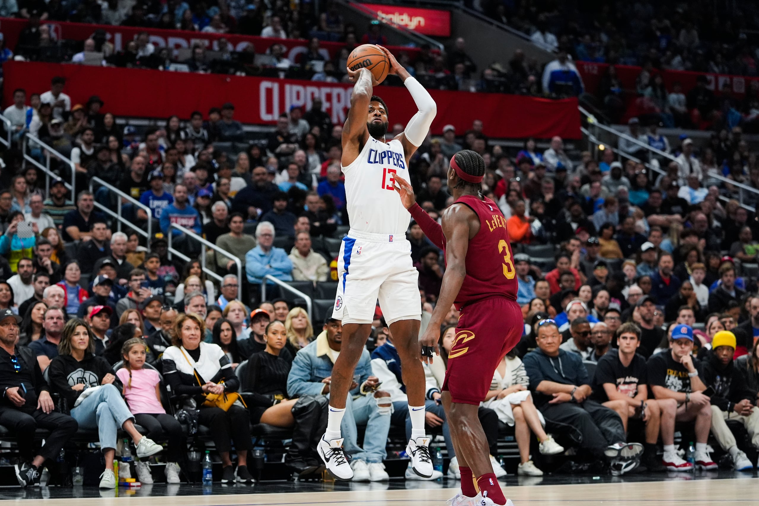 Paul George (13), alero de los Clippers de Los Ángeles, tira con la marca defensiva de Caris LeVert (3), de los Cavaliers de Cleveland, durante la segunda mitad del juego de baloncesto de la NBA, el domingo 7 de abril de 2024, en Los Ángeles. (AP Foto/Ryan Sun)