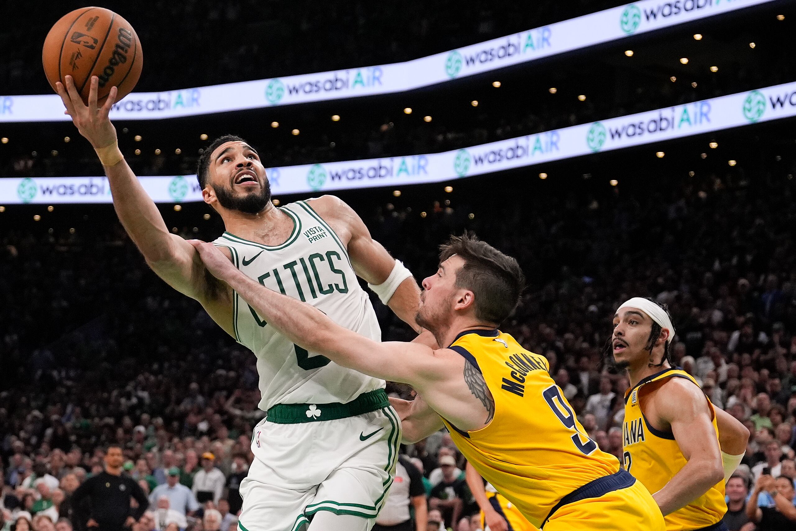 El alero de los Celtics de Boston, Jayson Tatum, lanza el balón frente al base de los Pacers de Indiana, T.J. McCollum.