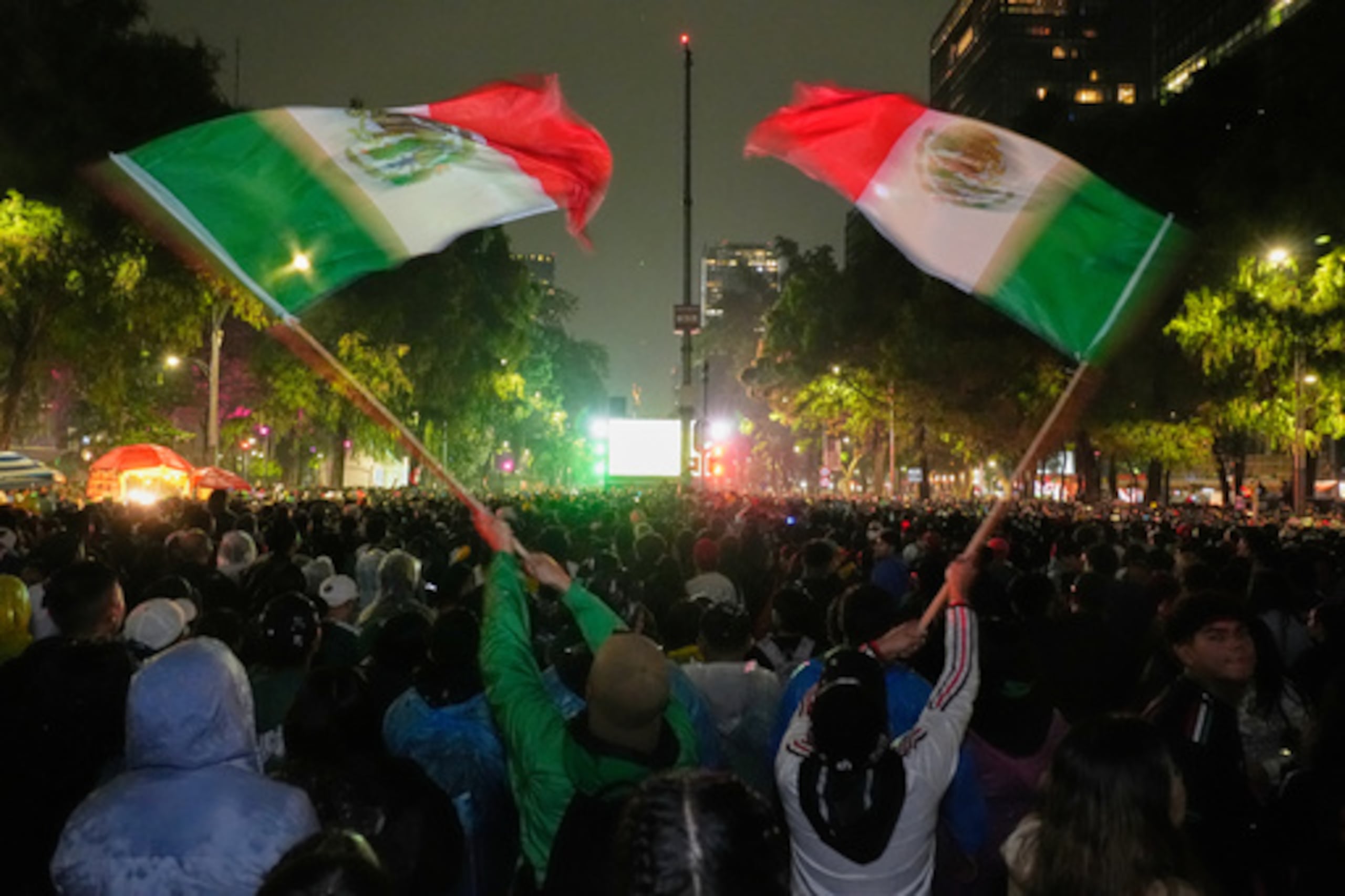 Los aficionados mexicanos agitan banderas mientras ven el partido de la ronda de 32 de la Copa del Mundo entre México y Ecuador, cerca del monumento al Ángel de la Independencia en Ciudad de México, el martes 30 de junio de 2026. (Foto AP/Marco Ugarte)