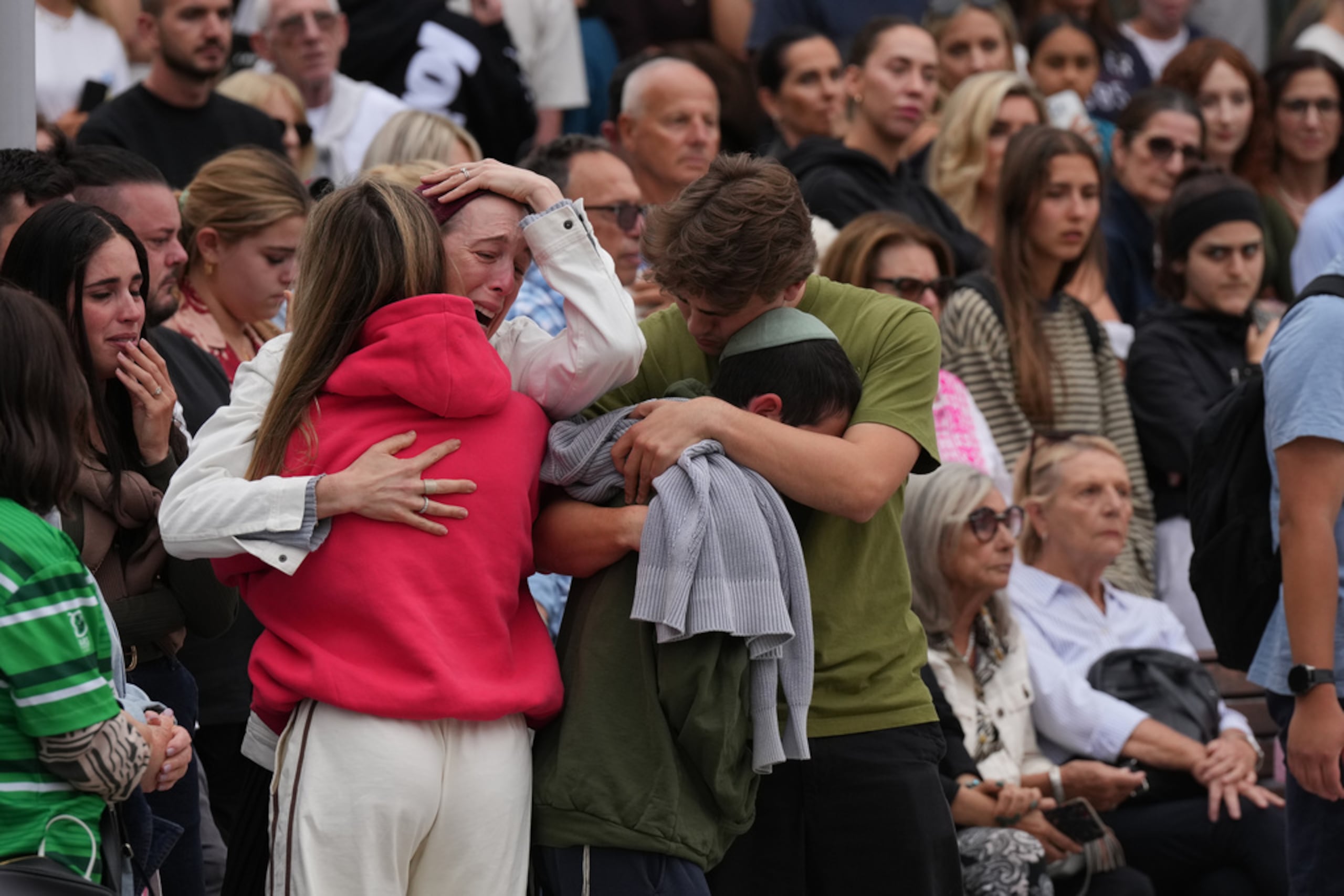 Familiares de una de las víctimas del tiroteo lloran en un memorial floral erigido tras el incidente, en el Bondi Pavilion este martes.