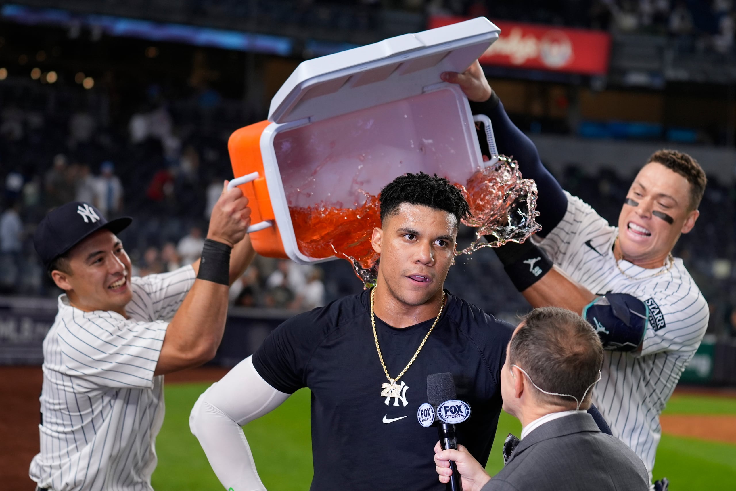 Anthony Volpe (izquierda) y Aaron Judge vacían la hielera encima del dominicano Juan Soto, su compañero de los Yankees de Nueva York, tras la victoria sobre los Red Sox de Boston.