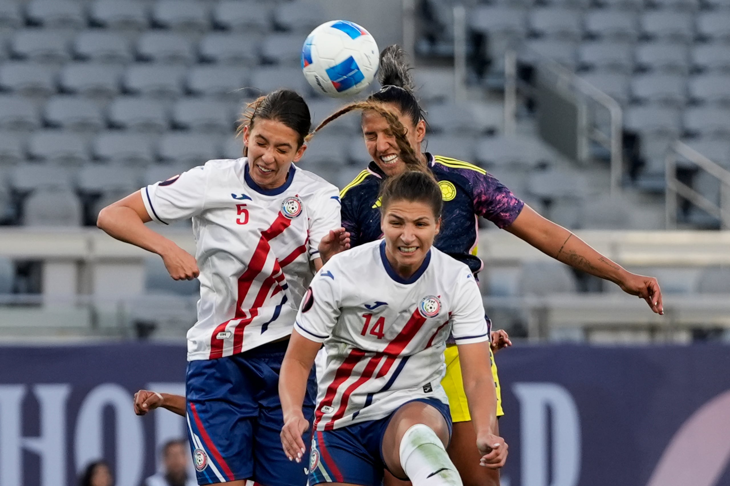 La colombiana Manuela Pavi cabecea el balón ante la defensa de las puertorriqueñas Jillienne Aguilera y Madison Cox.