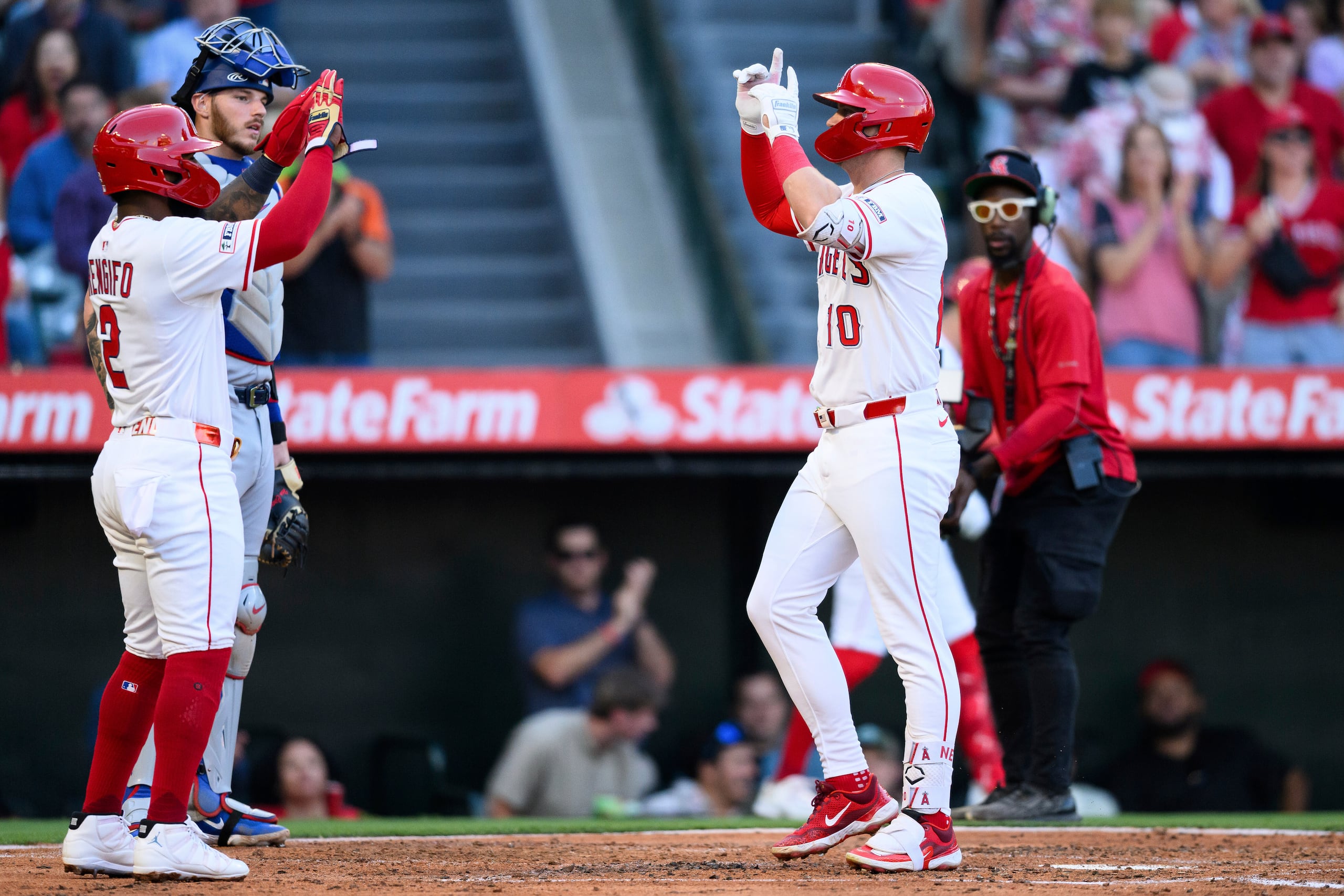 Kevin Newman, derecha, de los Angelinos de Los Ángeles, celebra luego de batear un jonrón durante la tercera entrada del juego de béisbol de Grandes Ligas contra los Rangers de Texas, el lunes 28 de julio de 2025, en Anaheim, California. (AP Foto/William Liang)