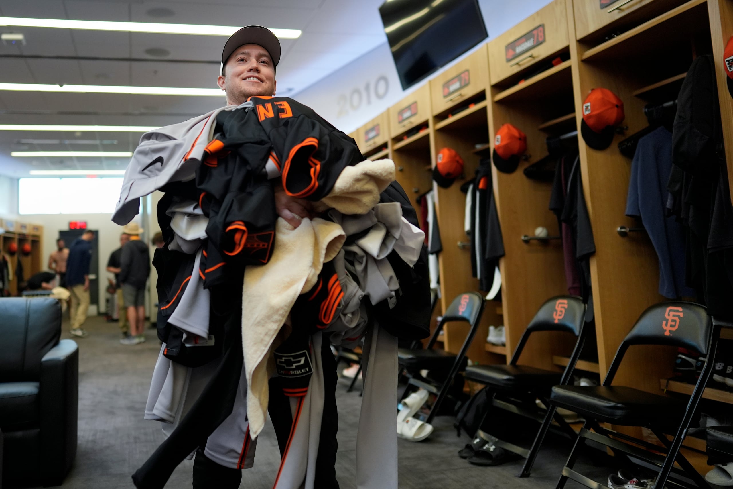 Riley Halpin, del personal de apoyo del clubhouse de los Giants, recoge una tanda de ropa sucia para llevarla a lavar en el cuarto de lavadoras del equipo.