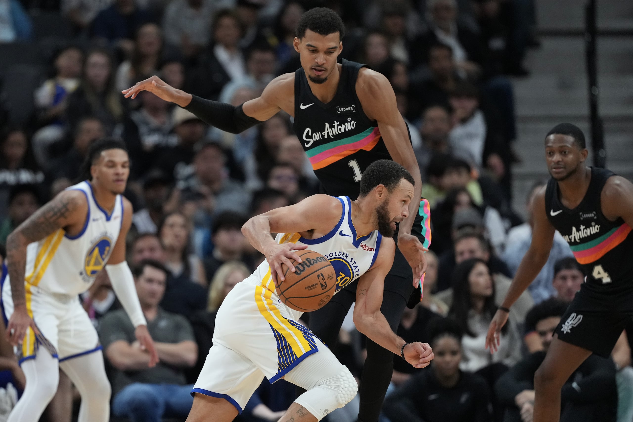 Stephen Curry (30), de los Warriors de Golden State, conduce el balón frente a Victor Wembanyama (1), de los Spurs de San Antonio, durante la segunda mitad del partido de baloncesto de la NBA, el miércoles 12 de noviembre de 2025. (AP Foto/Eric Gay)