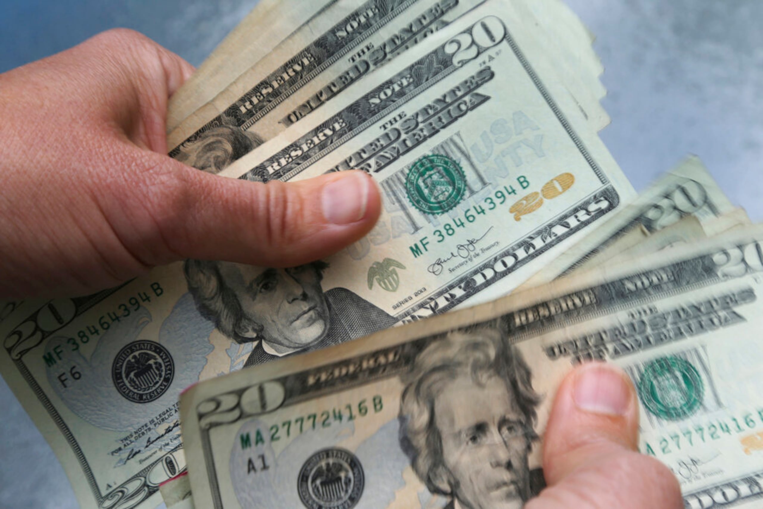 FILE - In this June 15, 2018, file photo, 20-dollar bills are counted in North Andover, Mass. Federal and state authorities say they are cracking down on a wave of illegal schemes, estimated to have bilked consumers out of more than $1 billion, that have proliferated during the coronavirus pandemic and prey upon the desperation of people who have lost jobs in the outbreak's economic upheaval. (AP Photo/Elise Amendola, File)