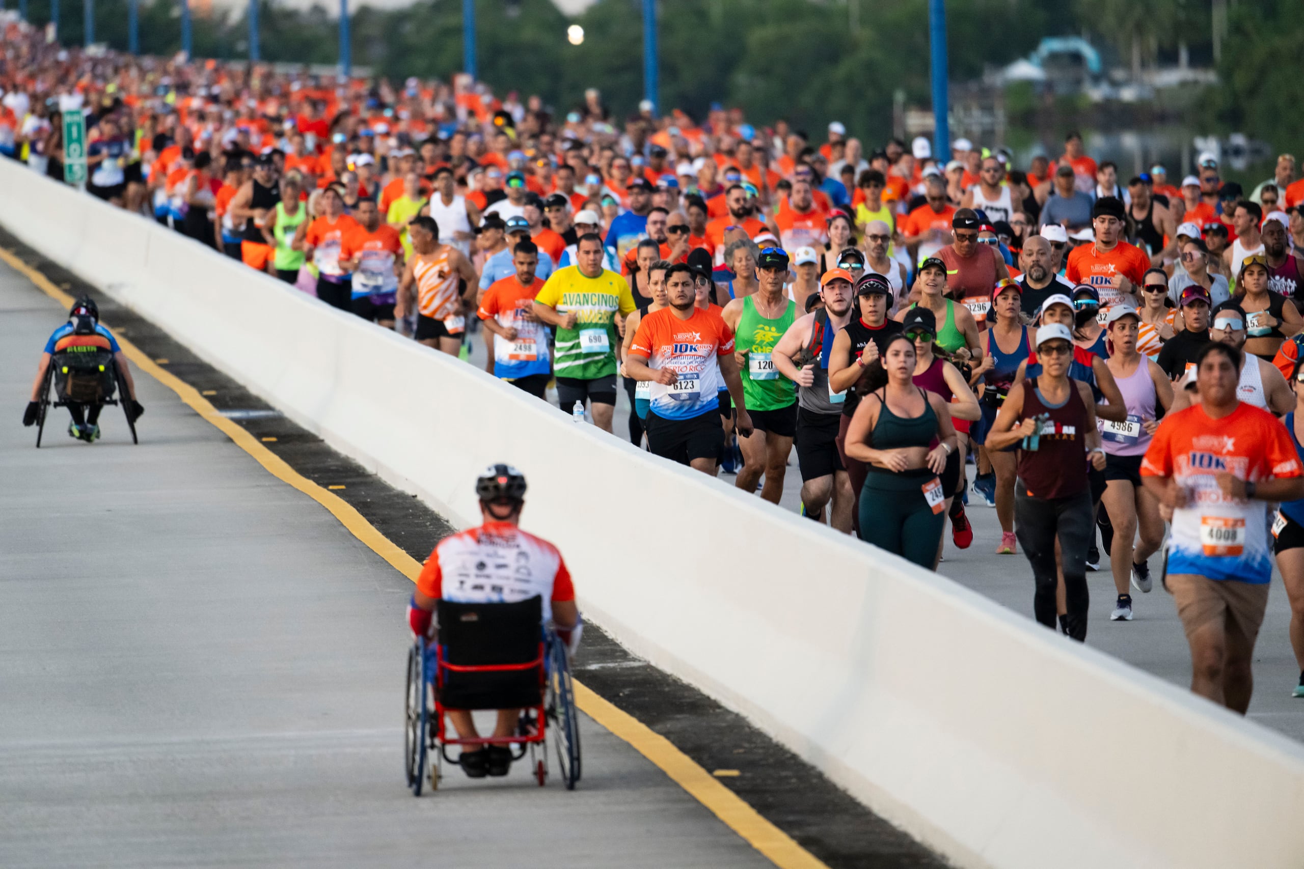 Cientos de miles de corredores hacen su parte y apoyan a la clase de silla de rueda durante el trayecto sobre el puente Teodoro Moscoso.