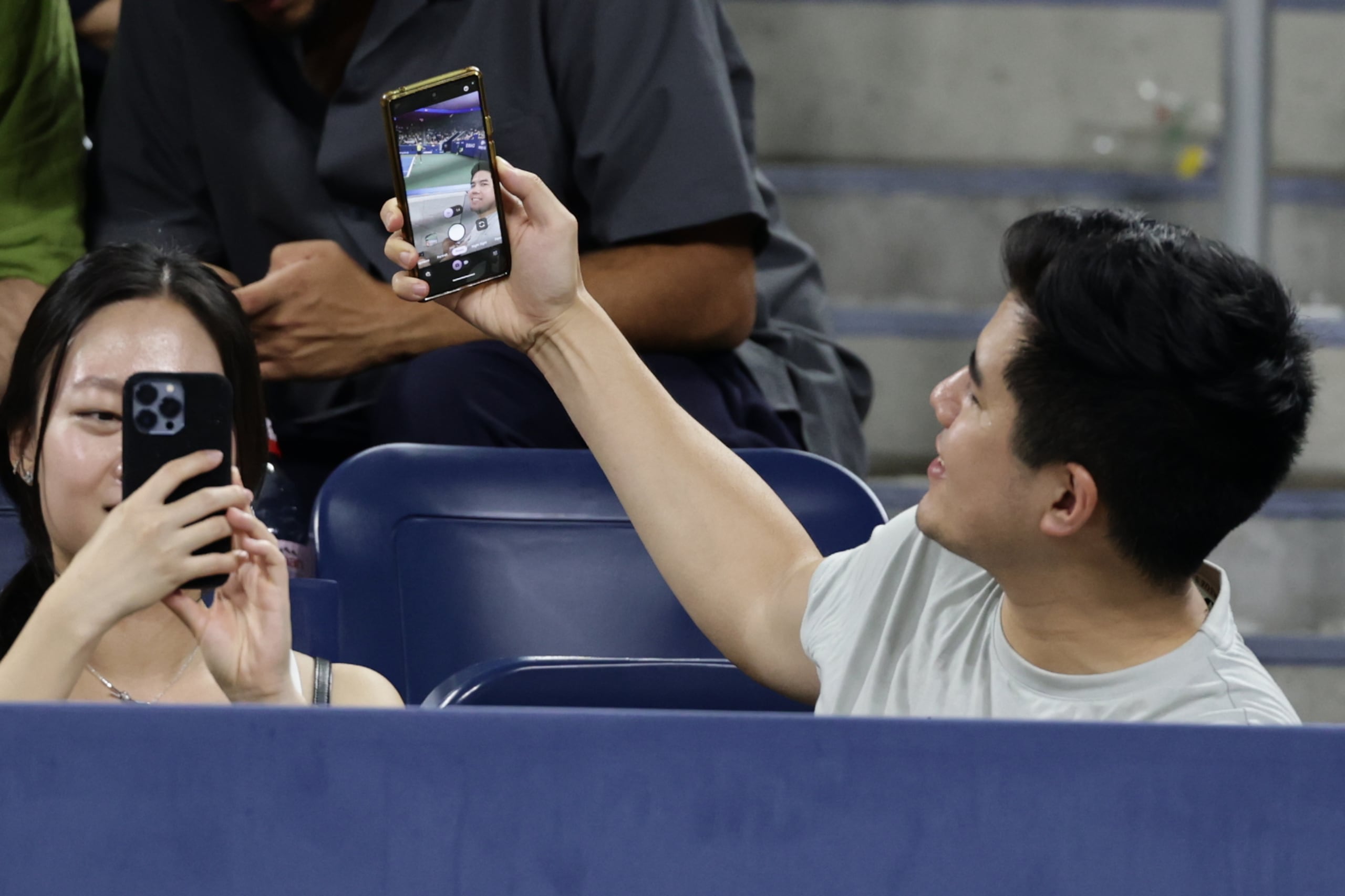Un aficionado se toma una selfie mientras la kazaja Elena Rybakina sirve ante la española Jessica Bouzas Maneiro durante la segunda ronda del Abierto de Estados Unidos.