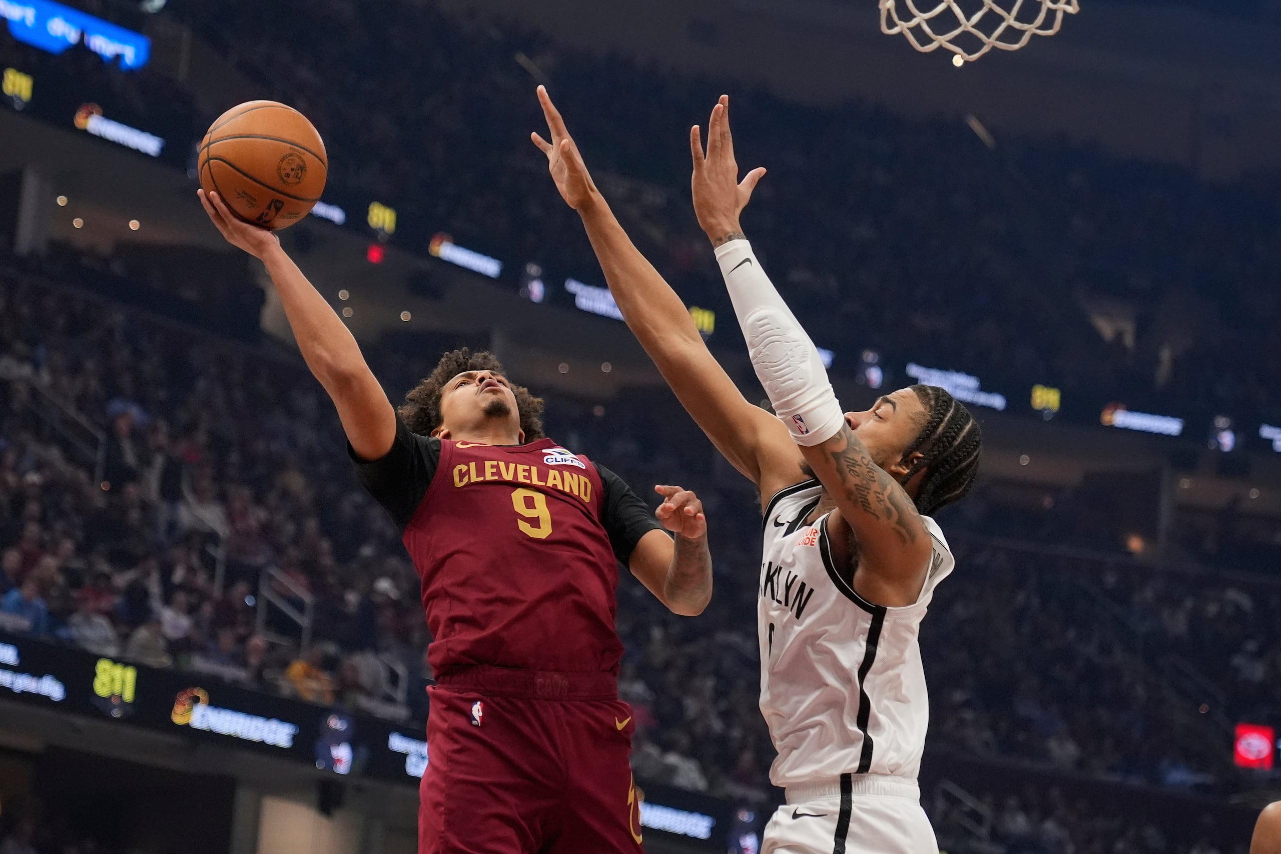 El base de los Cavaliers de Cleveland Craig Porter Jr. lanza el balón frente a Trenton Watgford de los Nets de Brooklyn.