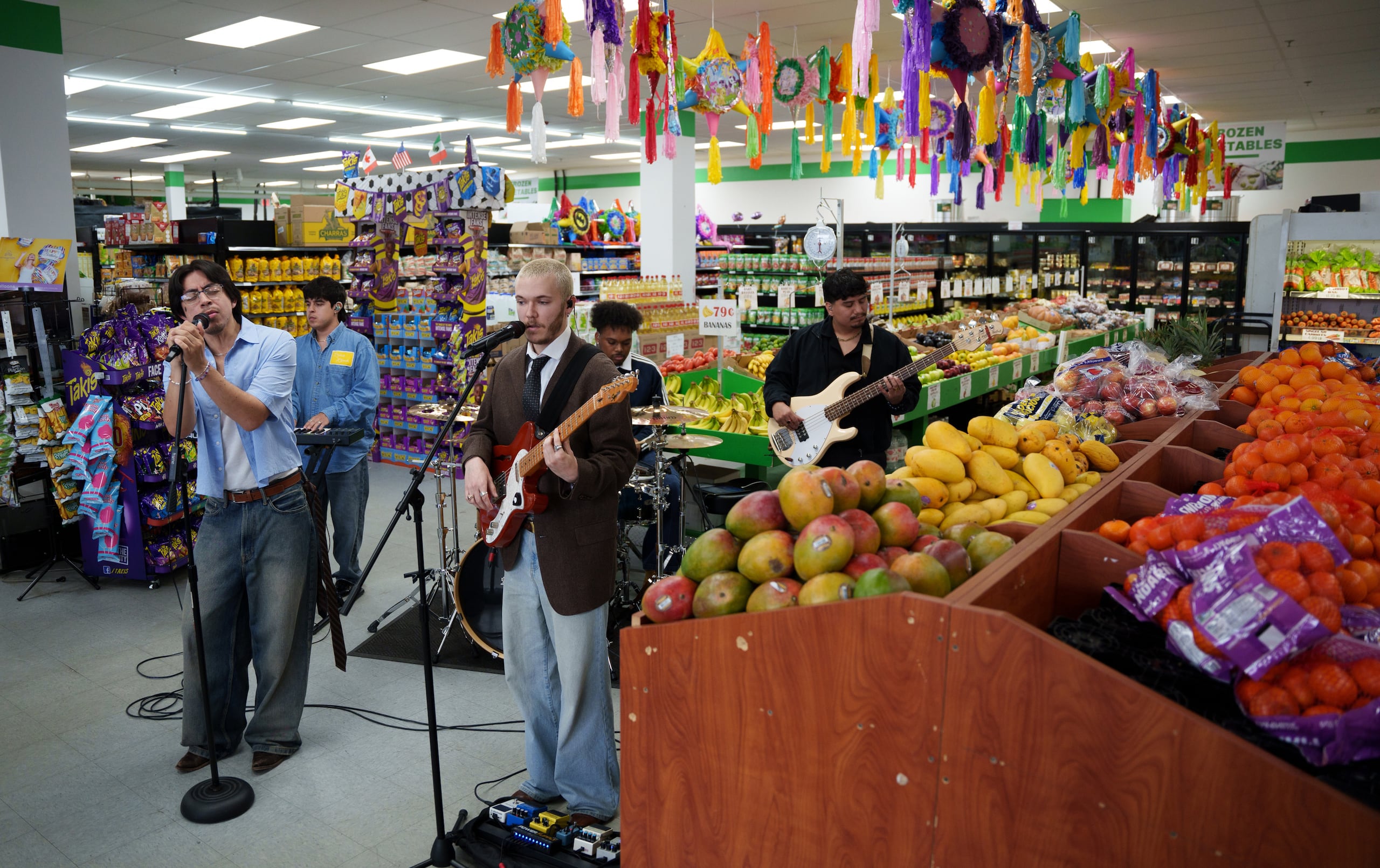 El grupo bilingüe de pop alternativo Luna Luna actuó en la sección de frutas y verduras del mercado Fiesta Fresh Market en New Castle, Delaware, el domingo 26 de abril de 2026. (Foto AP/Mingson Lau)
