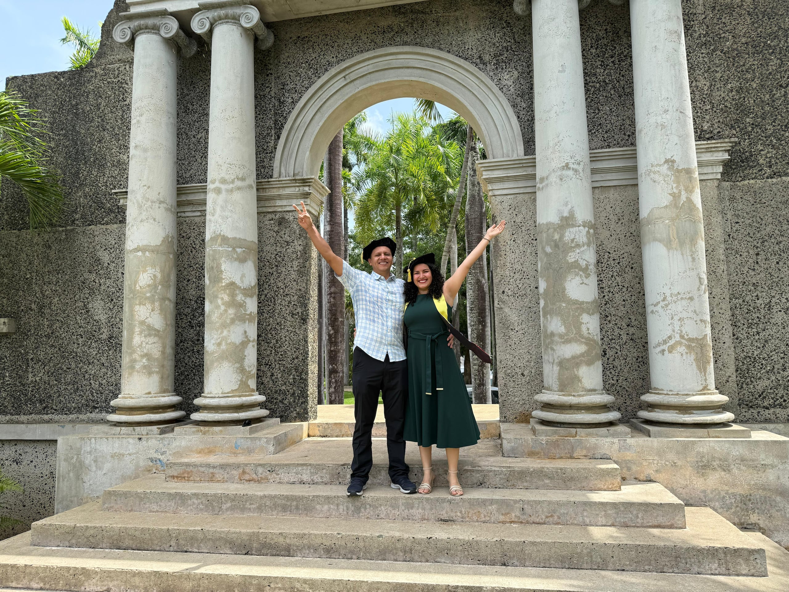 Margie Guerrero Fernández y Juan Carlos Vargas Martínez posan con sus birretes frente al portal del RUM.