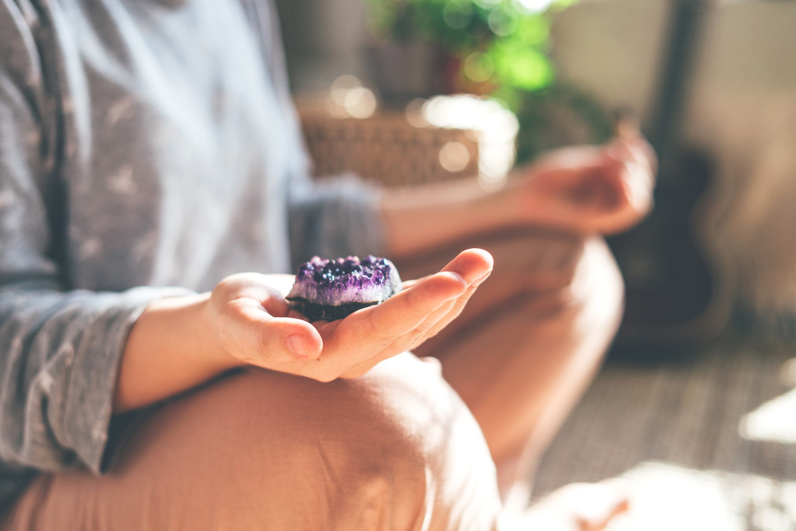 Una mujer meditando con una amatista en la mano.