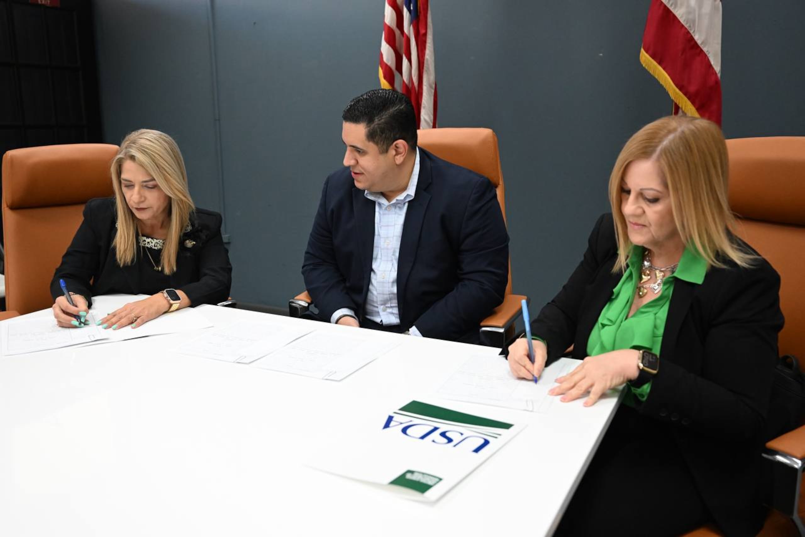 La directora ejecutiva de la Autoridad de Tierras, Helga Méndez Soto (izquierda), el secretario de Agricultura, Josué Rivera Castro (centro), y la directora ejecutiva estatal de la FSA en Puerto Rico, Wanda Pérez (derecha), firmando el traspaso de tierras.