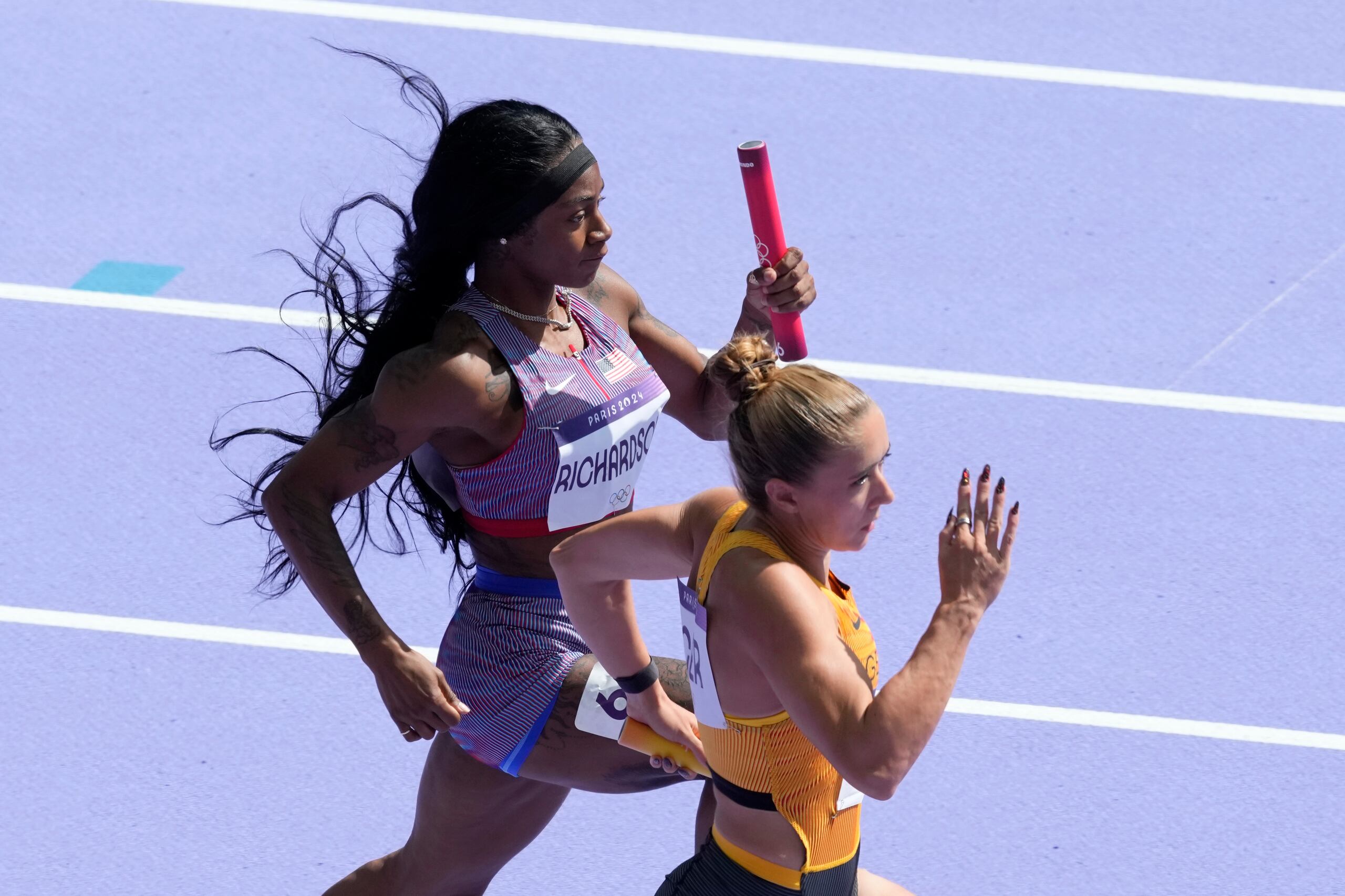 La estadounidense Sha'carri Richardson y la alemana Rebekka Haase compiten en las eliminatorias del relevo 4x100 femenino de los Juegos Olímpicos de París, el jueves 8 de agosto de 2024, en Saint-Denis, Francia. (AP Foto/Martin Meissner)