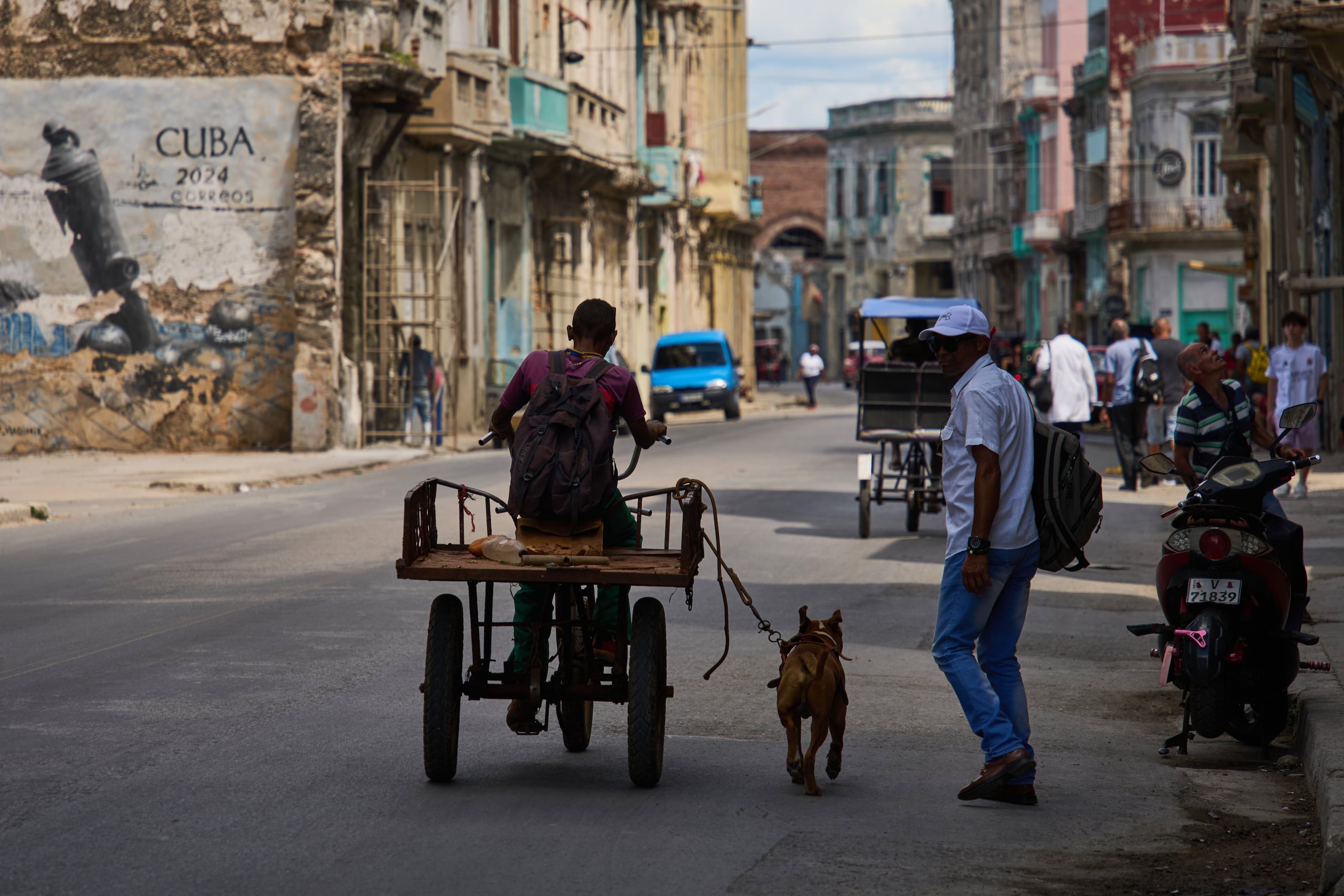 Un hombre monta en triciclo con su perro atado con correa corriendo a su lado durante un apagón en La Habana, Cuba, el lunes 16 de marzo de 2026.