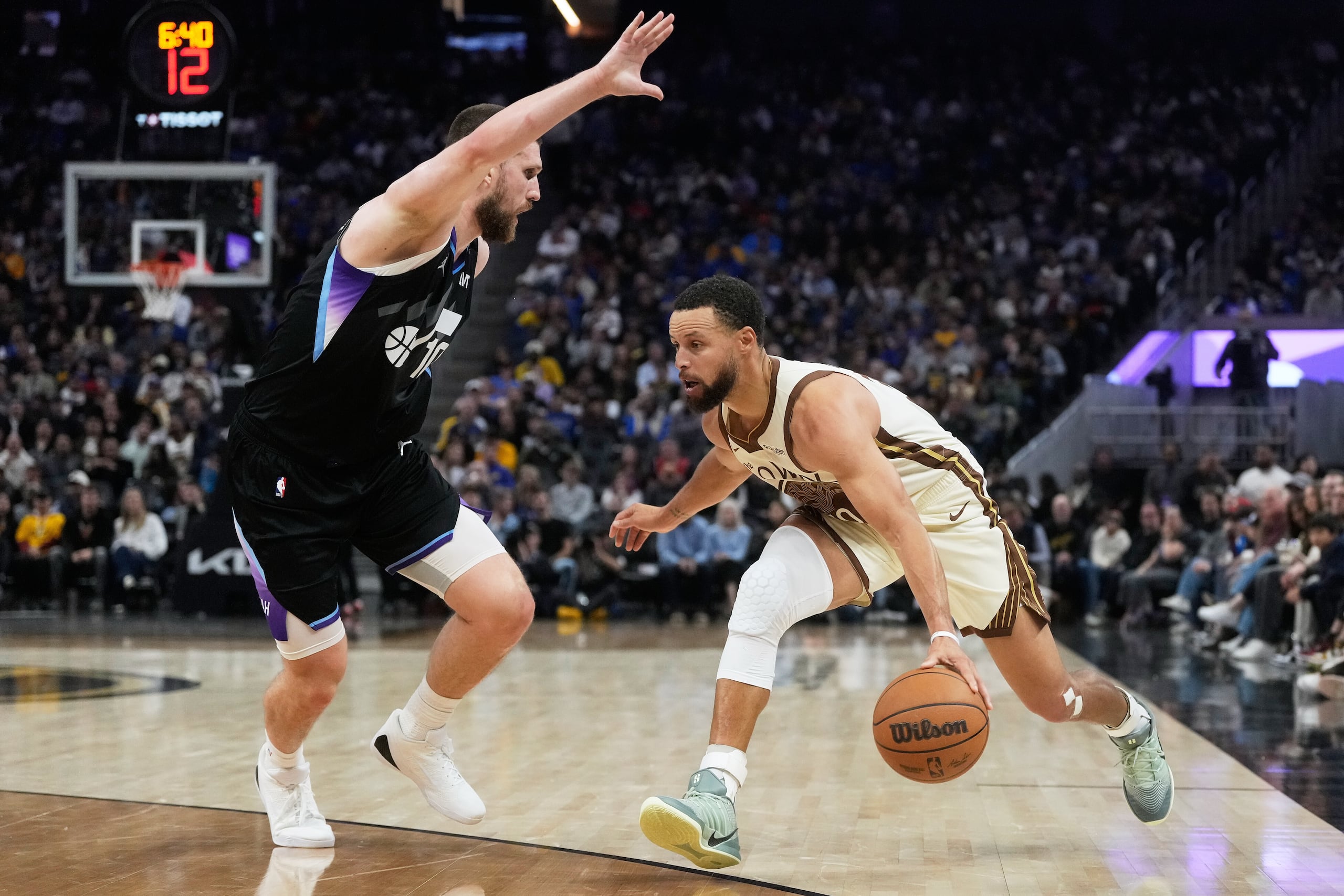 Stephen Curry, derecha, de los Warriors de Golden State, alista un tiro frente a Svi Mykhailiuk, del Jazz de Utah, durante la segunda mitad del juego de baloncesto de la NBA, el lunes 24 de noviembre de 2025, en San Francisco. (AP Foto/Jeff Chiu)