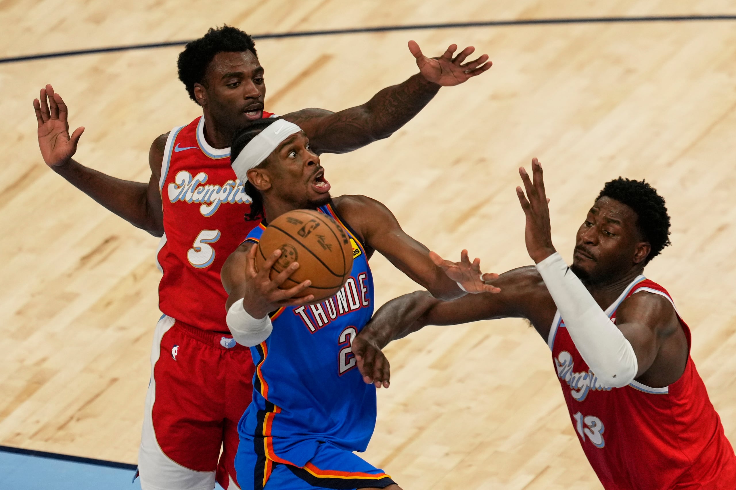 Shai Gilgeous-Alexander, del Thunder de Oklahoma City,  trata de atacar el canasto frente a  Vince Williams Jr. y Jaren Jackson, ambos de los Grizzlies de Memphis.