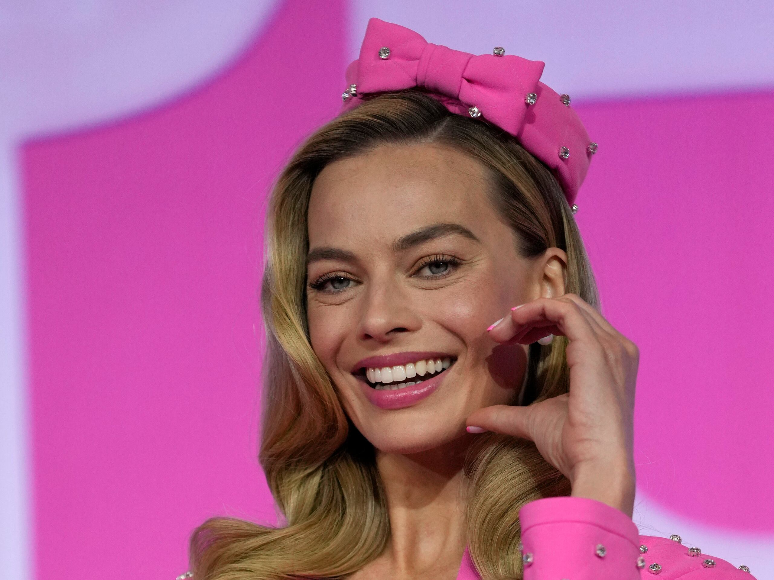 Para una conferencia de prensa de la película en Seúl, Corea del Sur, la actriz usó un set rosado compuesto por un abrigo, un bralette y una falda de Moschino con tachuelas plata inspirado en la “Sparkling Pink Barbie” del 1964. Lo combinó con un lazo rosado, un bolso en forma de corazón de Moschino, unos tacones rosados de Manolo Blahnik y unas pantallas de perlas de Tiffany & Co.