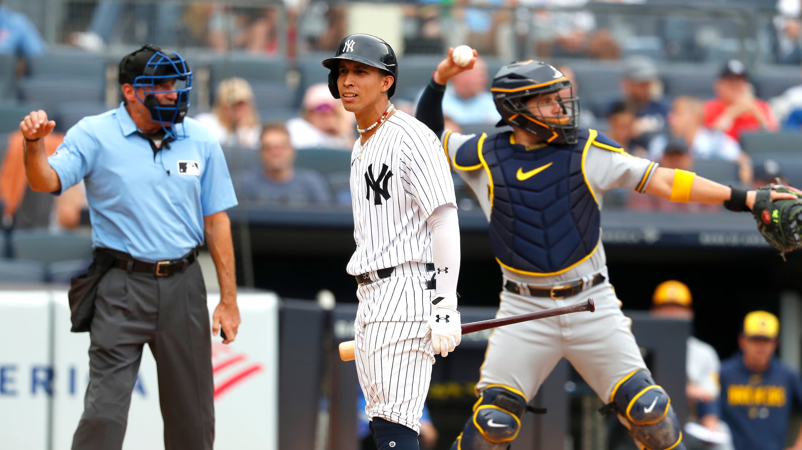 El receptor de Milwaukee, Víctor Caratini, en segundo plano, le devuelve al lanzador de Milwaukee la pelota luego de ponchar a Oswaldo Cabrera.